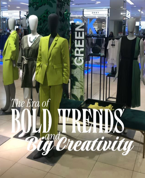 Display of mannequins dressed in bold, colorful fashion outfits in a shopping mall, with signs reading 'GREEN' and text overlay that says 'The Era of BOLD TRENDS and Big Creativity'.