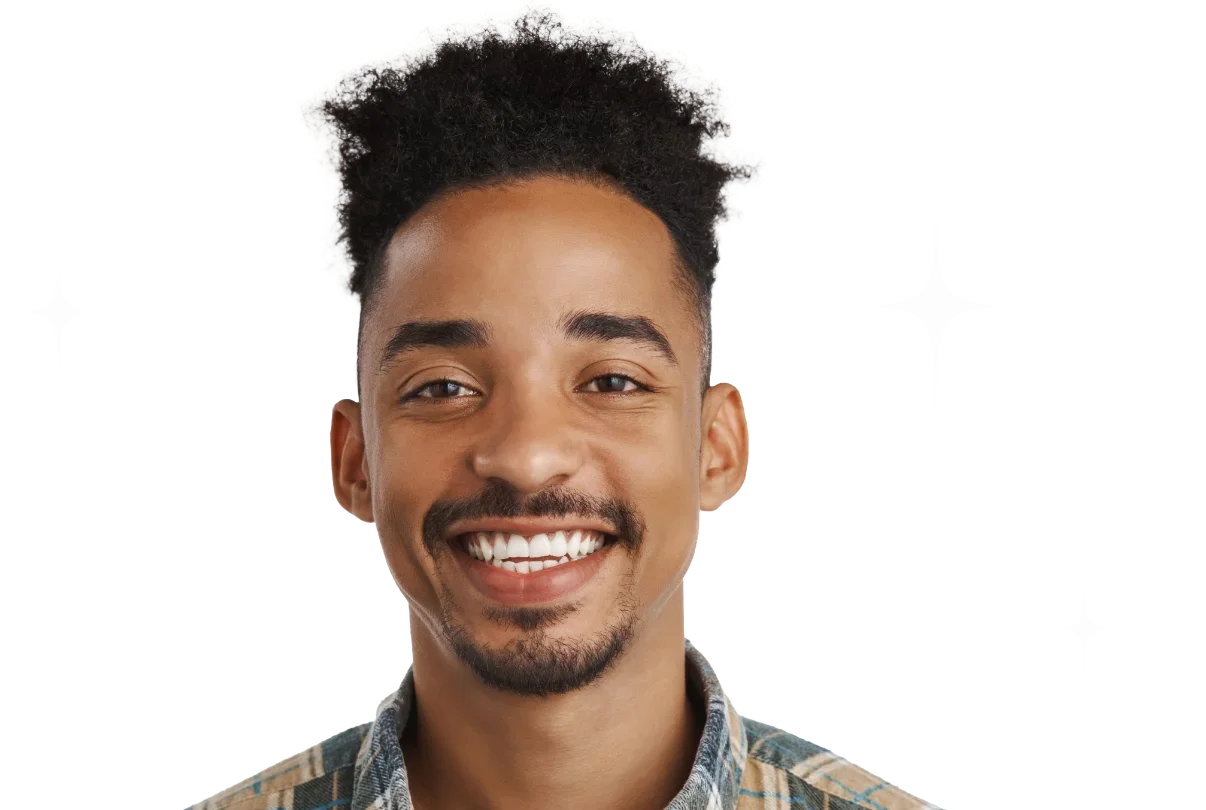 Un homme souriant avec des cheveux noirs bouclés et une barbe, portant une chemise à carreaux.