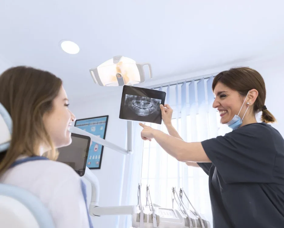 Une dentiste montre une radiographie dentaire à une patiente dans un cabinet dentaire.