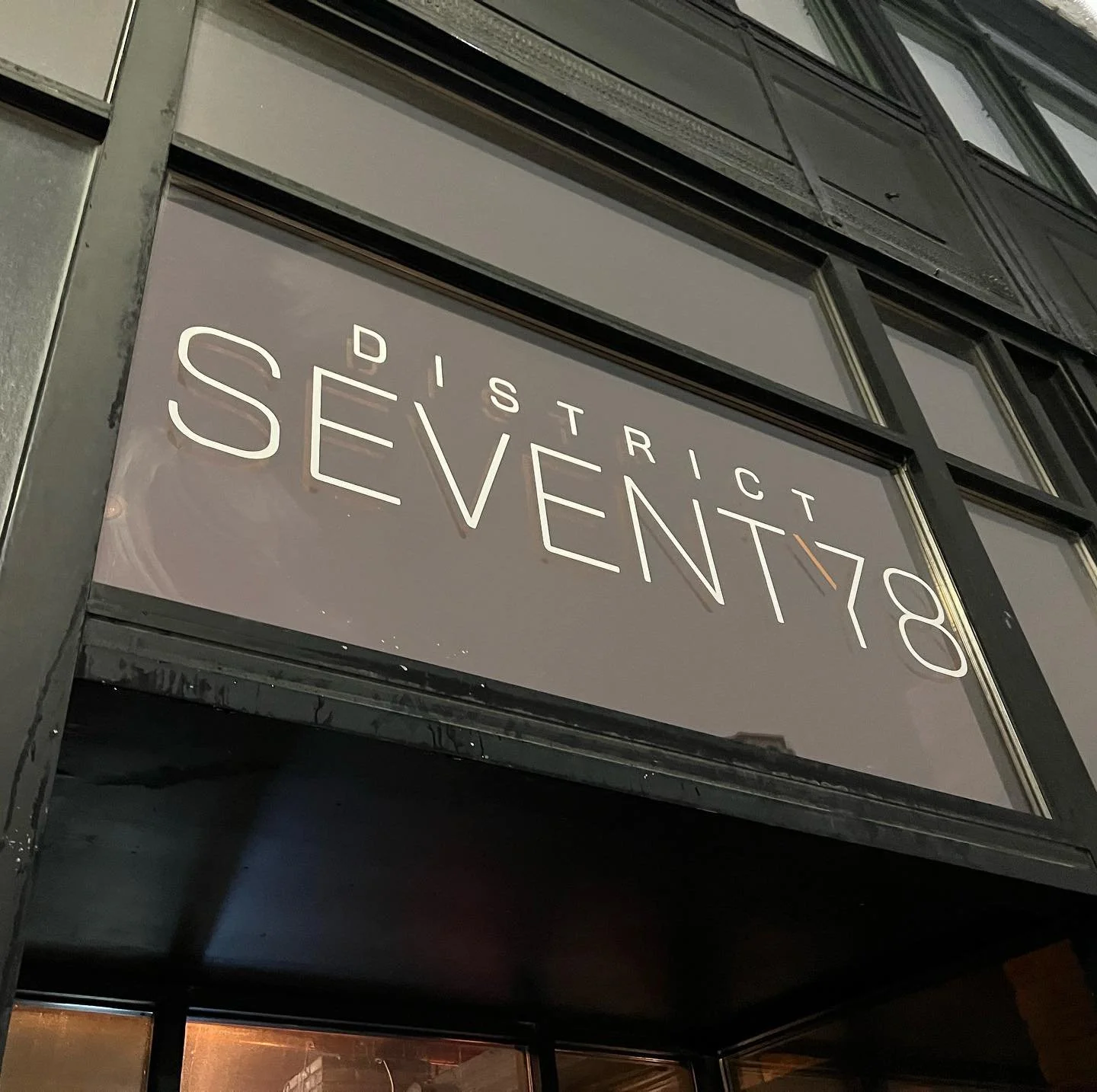 Sign reading 'District Seven' at night on a building exterior.