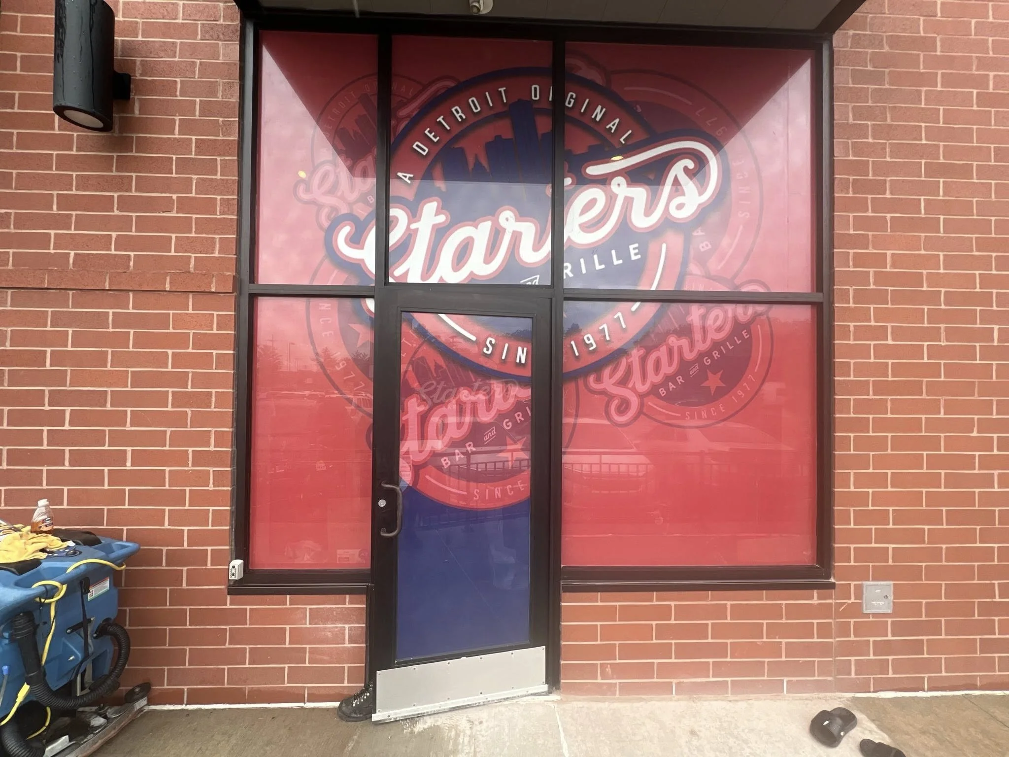 Storefront window with a large red and pink logo for Stahlers, a bar and grill in Detroit, established since 1977.
