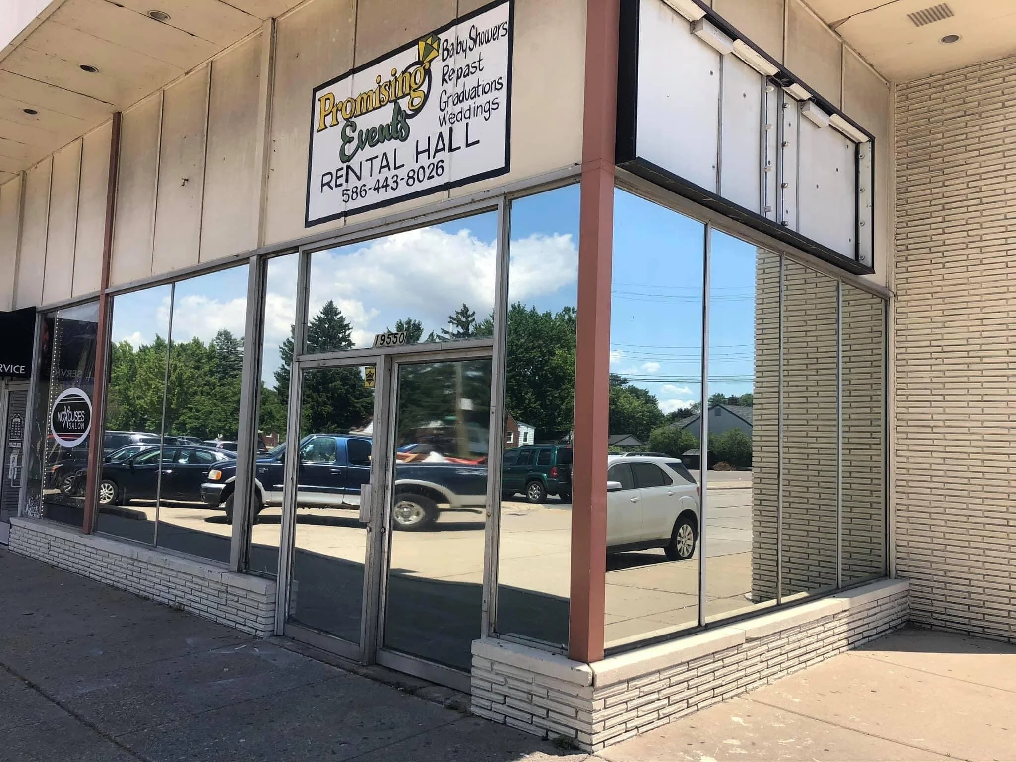 The storefront of Promising Events Rental Hall with glass windows and a sign displaying services like baby showers, reups, graduations, and weddings. The parking lot is visible with several cars parked outside on a sunny day.