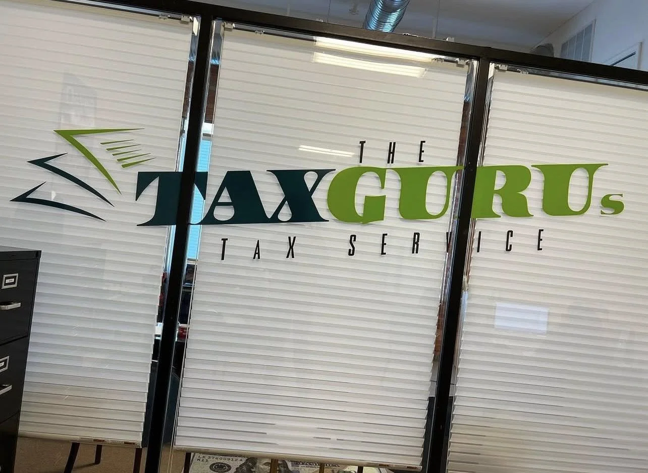 Glass door with a sign for 'The Tax Gorus Tax Service' featuring a logo with green and black lines.