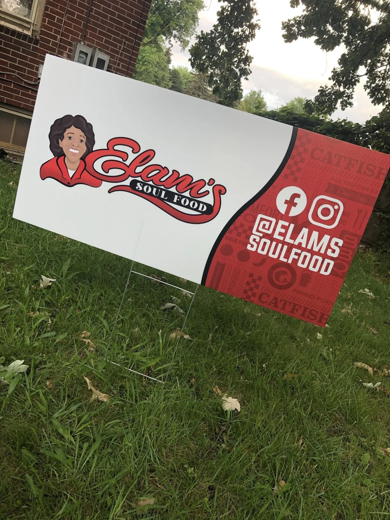 Signboard for Elam's Soul Food with a cartoon image of a woman, social media icons for Facebook, Instagram, and Twitter, and the handles @ELAMS SOULFOOD.