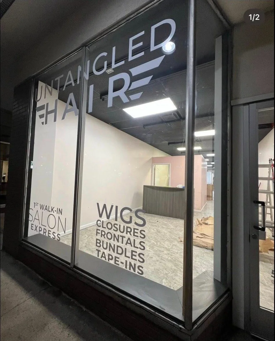 Empty salon space under construction with signage for wig services.