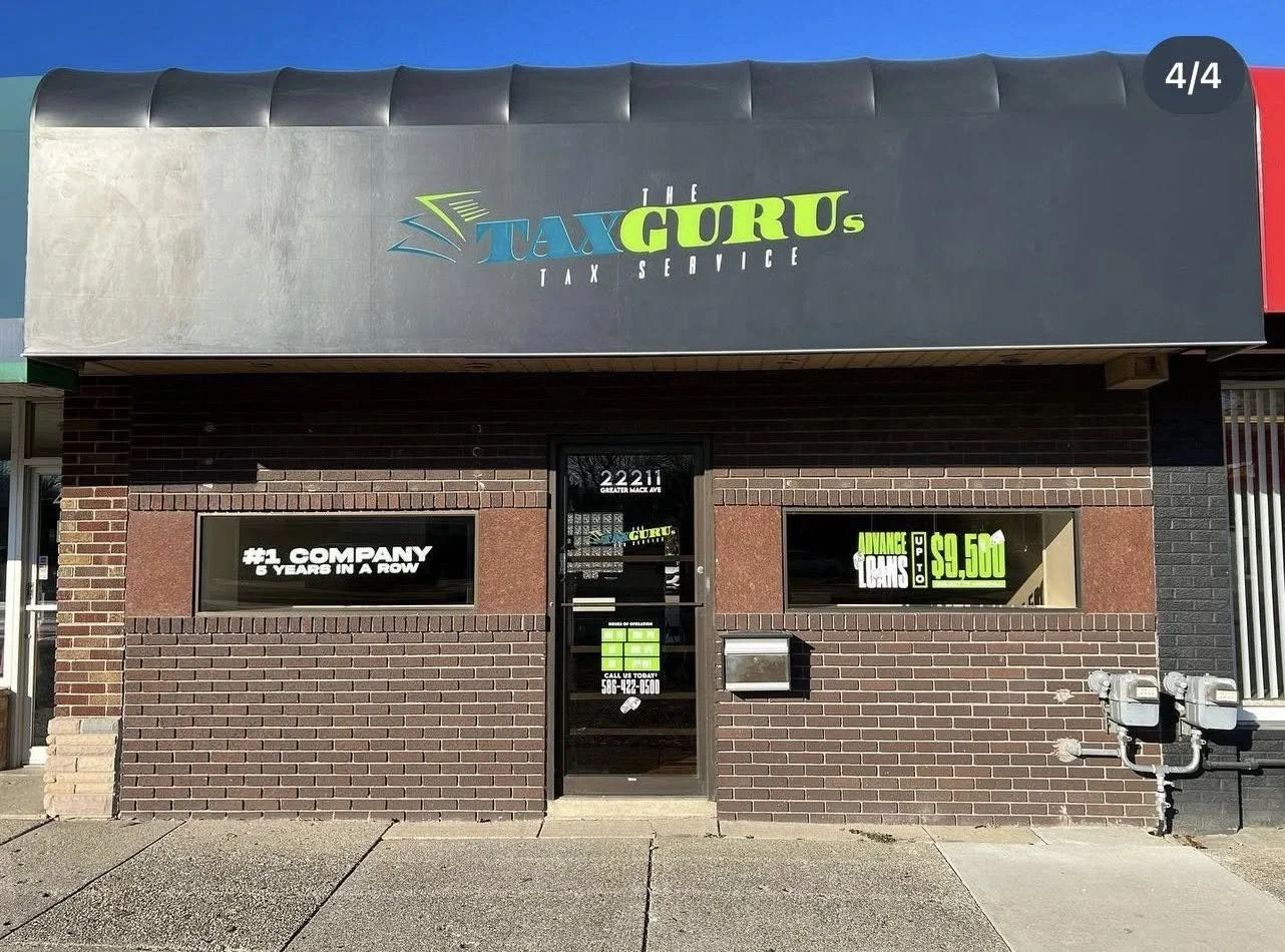 Brick storefront with a sign reading "Tax Gurus Tax Service" at the top, windows with promotional signs, and a door with a sign displaying a phone number, address, and promotional offers.