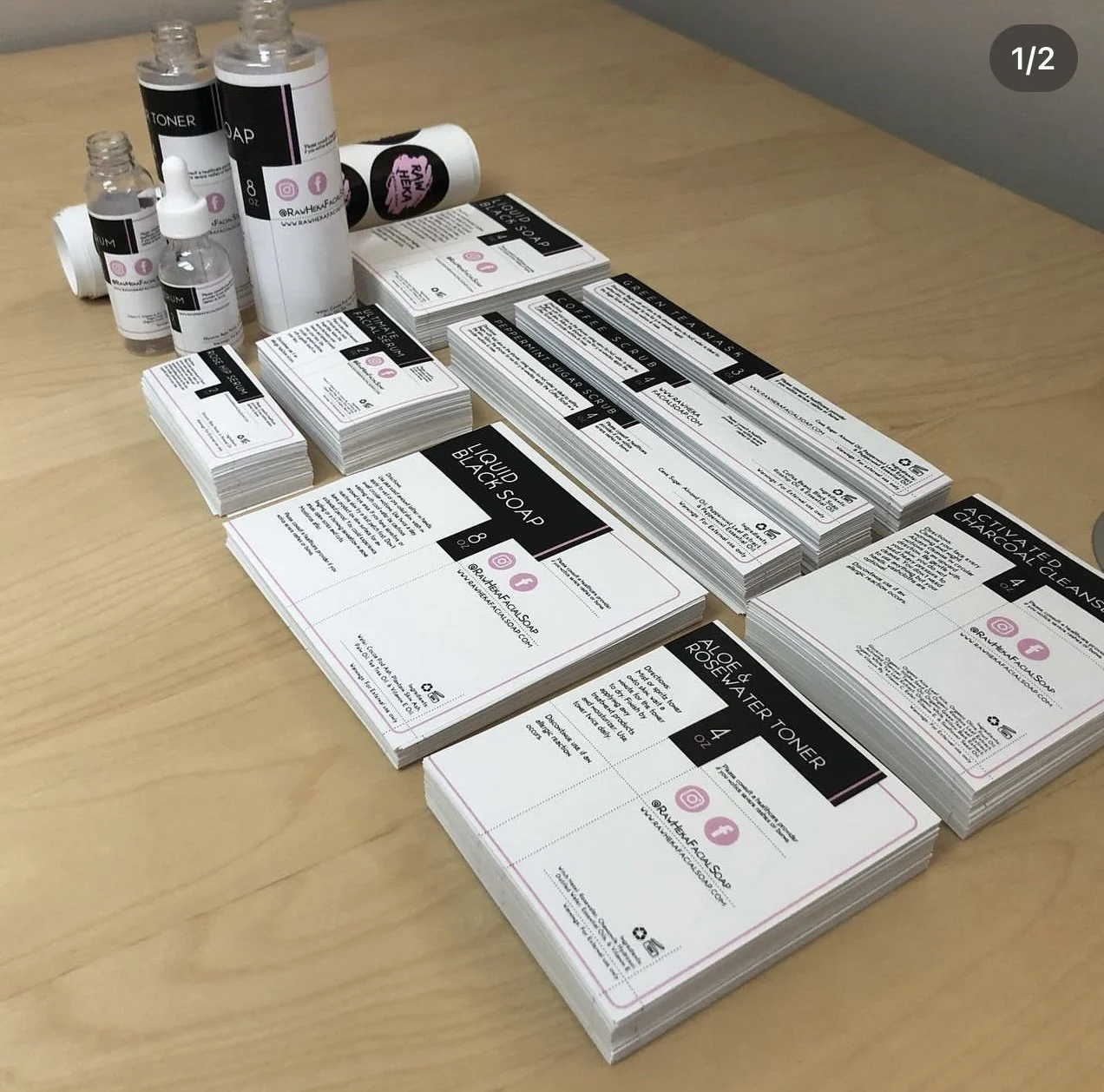 Collection of skincare product samples, including liquid black soap, aloe and rose water toner, activated charcoal cleaner, and various bottles of toner, soap, and serum, arranged on a wooden table.