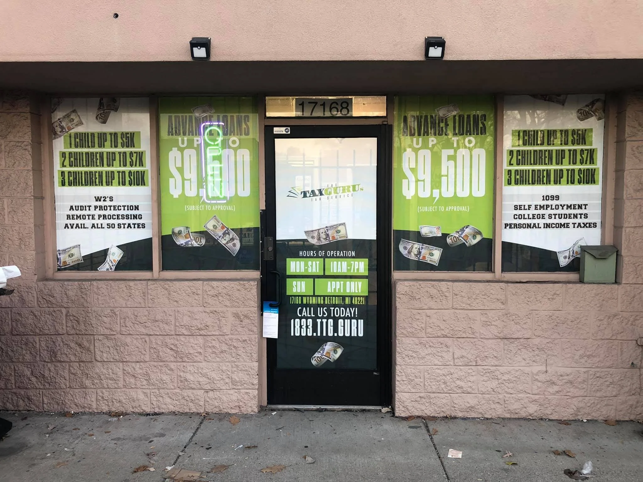 The storefront of a tax service office with large green signs advertising loans and financial services, decorated with fake dollar bills taped to the windows and door.