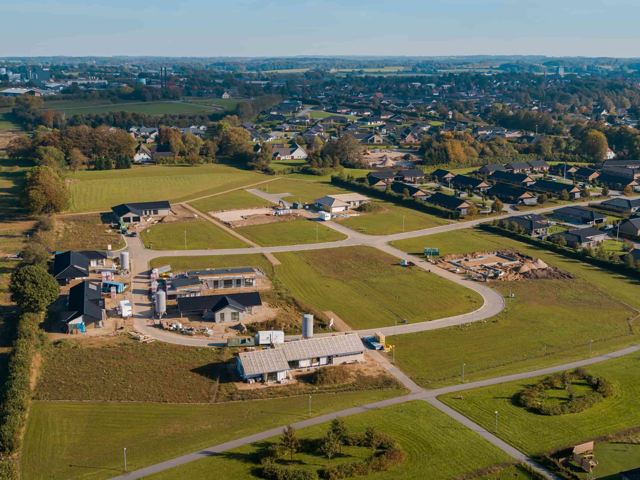 Dronefoto af boligområdet Linde Allé og Platan Allé med enkeltstående huse, grønne områder og veje, og grundarealer til nye huse under opførelse i et boligområde.