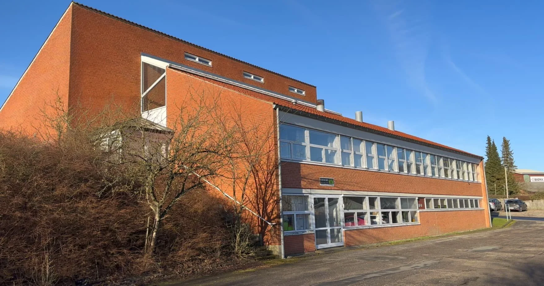 En redbrun murstensbygning på Gørtlervej i Ringe med mange store vinduer.