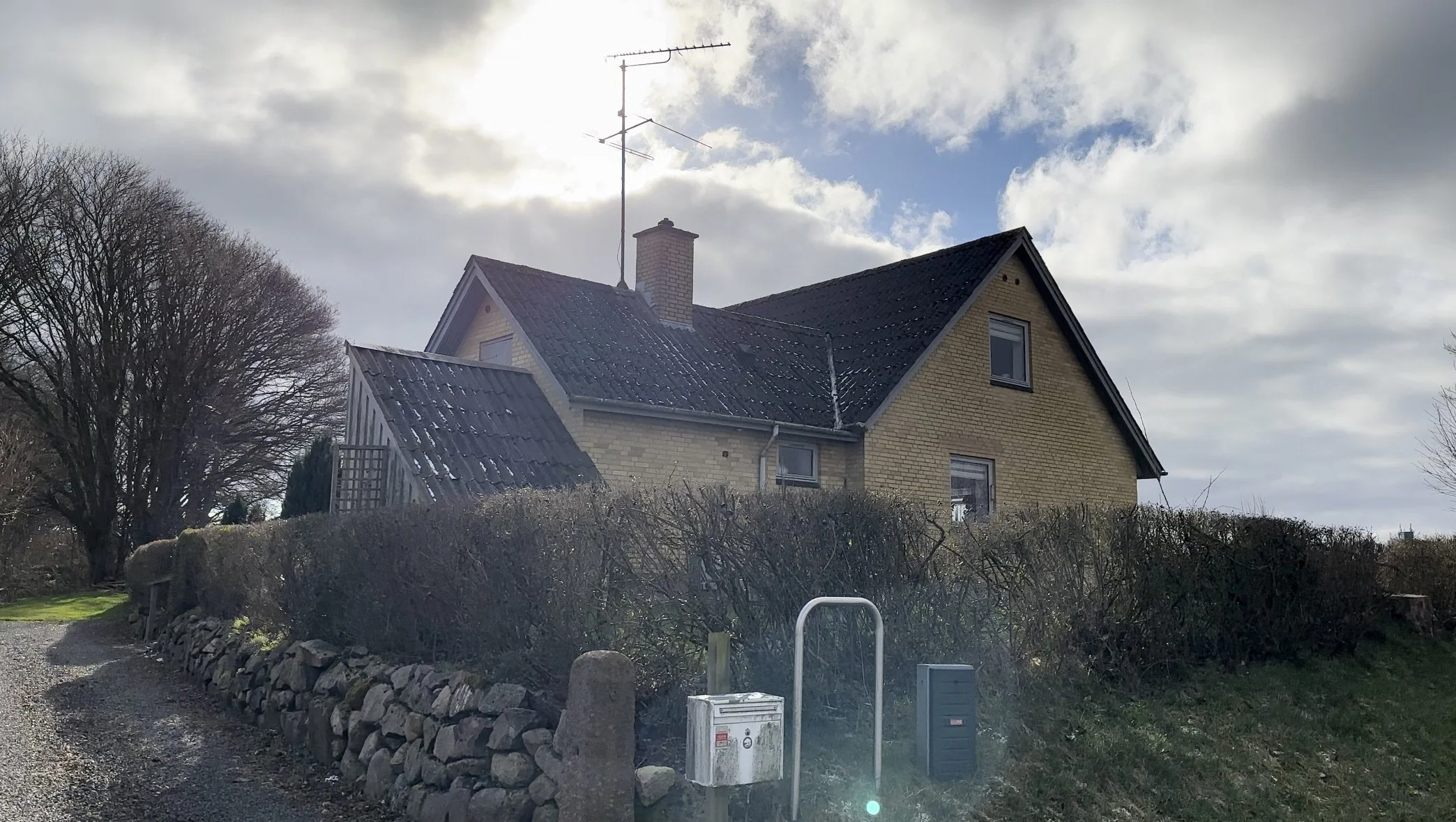Et villa hus i Ringe, omgivet af en buskads, stenmur og en grussti.
