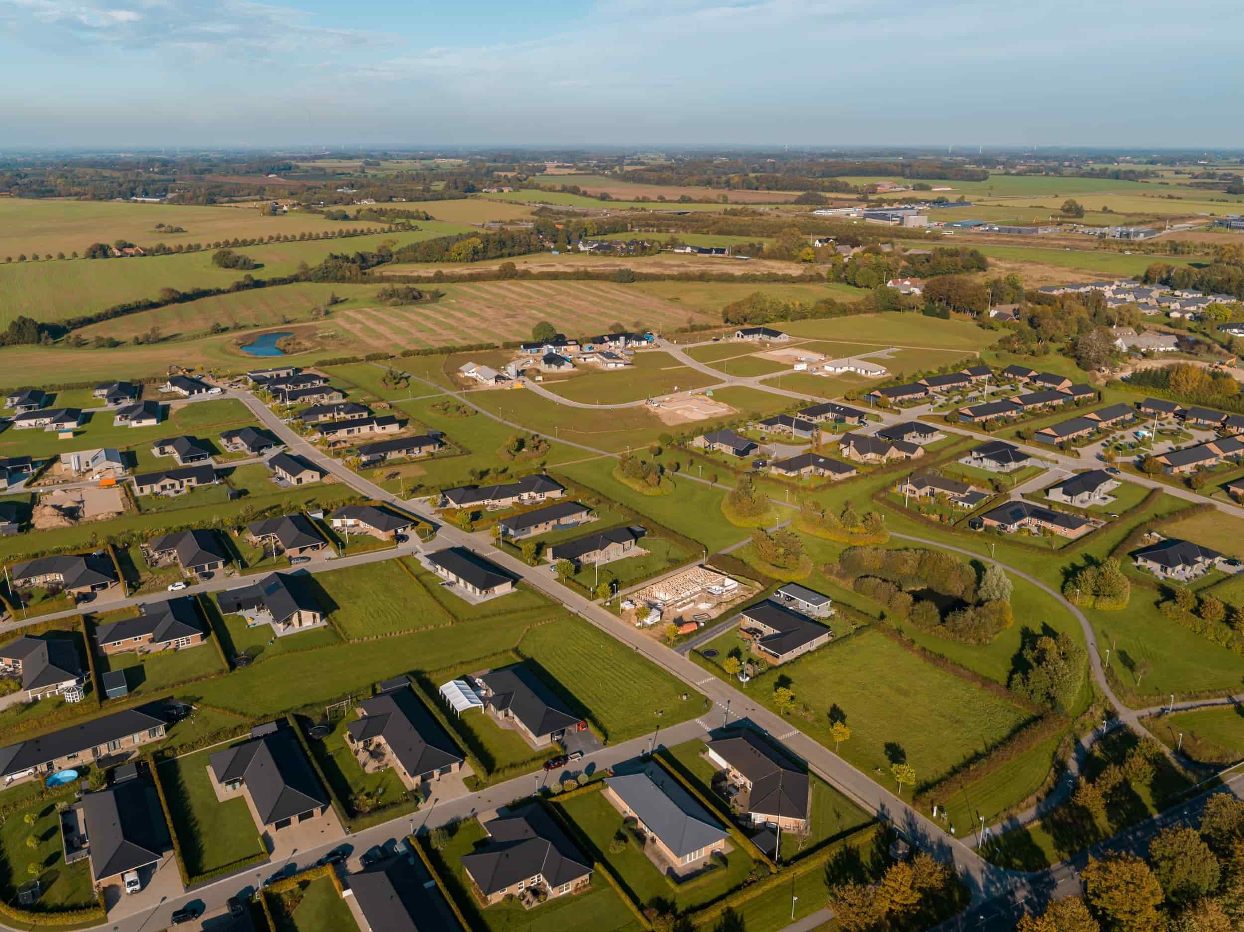 Dronefoto af boligområdet Linde Allé og Platan Allé med enkeltstående huse, grønne områder og veje, omgivet af åbne marker og landbrugsjord.