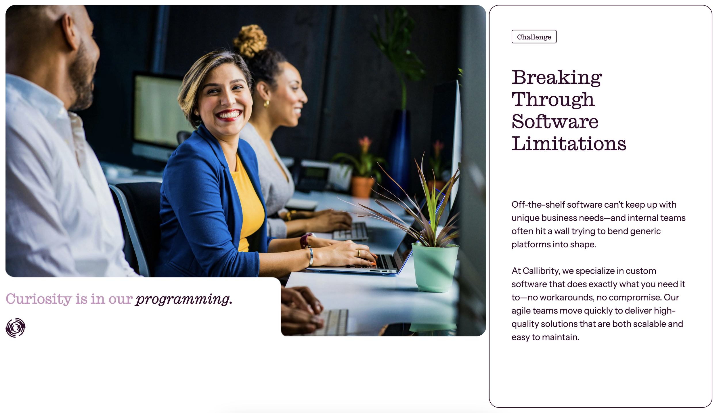 Group of three people sitting at a table in a modern office, smiling and working on laptops, with plants and computer monitors in the background.