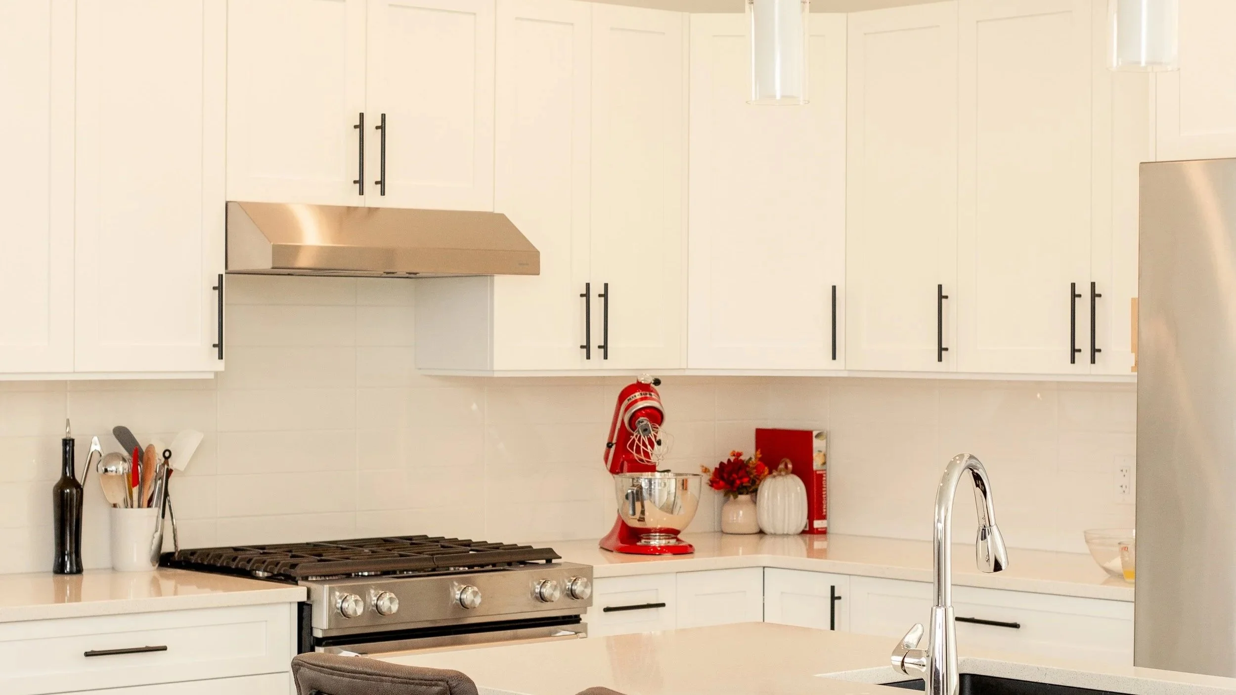 Modern kitchen with white cabinets, stainless steel appliances, red stand mixer, and holiday decorations