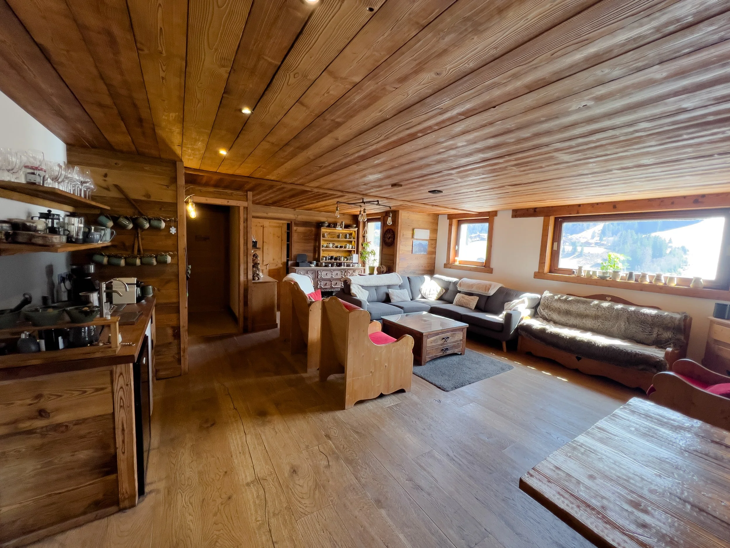 Cosy Alpine chalet living room in Les Gets with wood-panelled interior, comfortable sofas, and natural light.