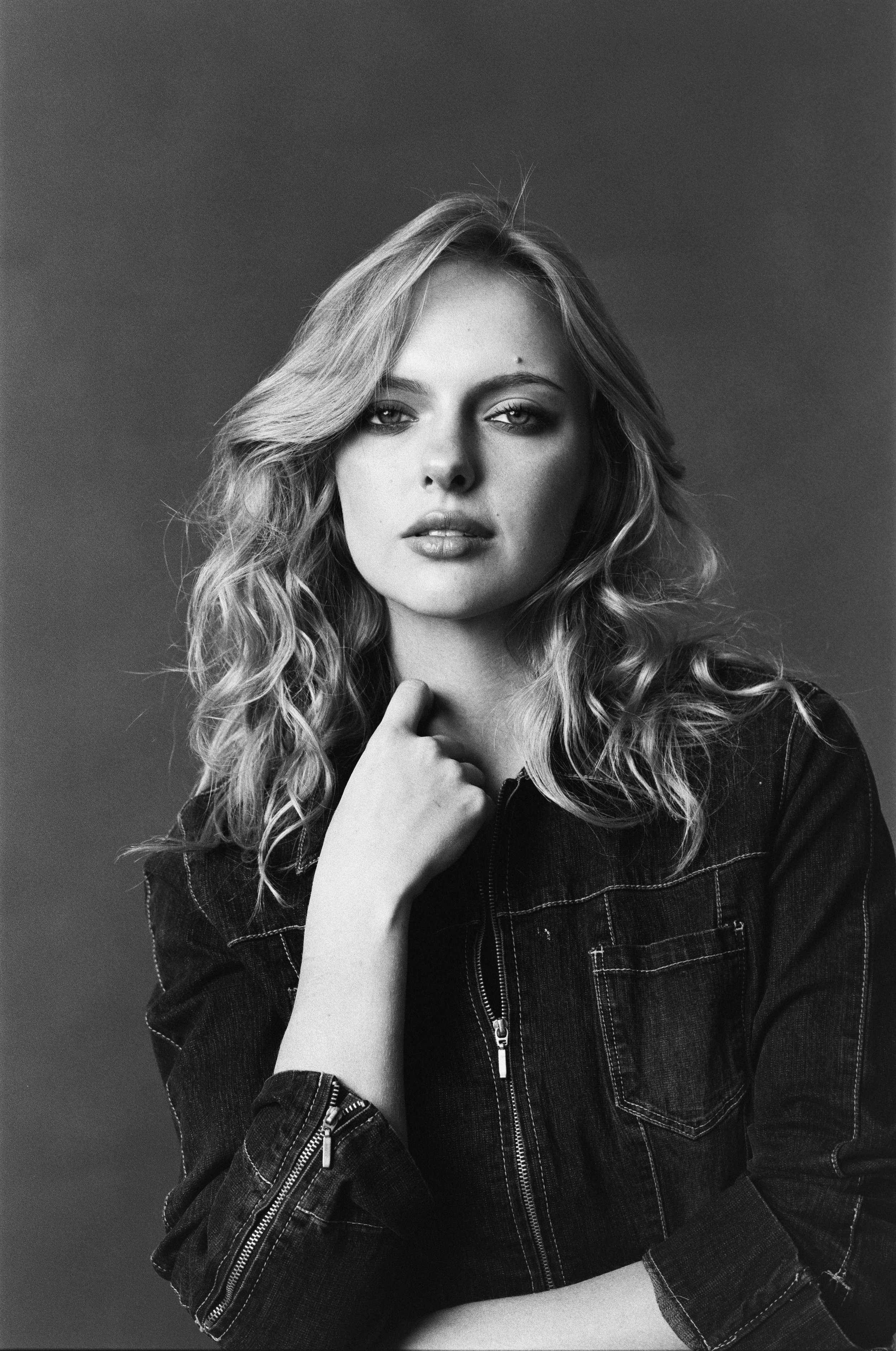 Black and white portrait of a young woman with wavy hair wearing a denim jacket, looking directly at the camera with a serious expression. Actress, Jessica Belkin, Acting headshot, Actor Portrait, Studio Portraits