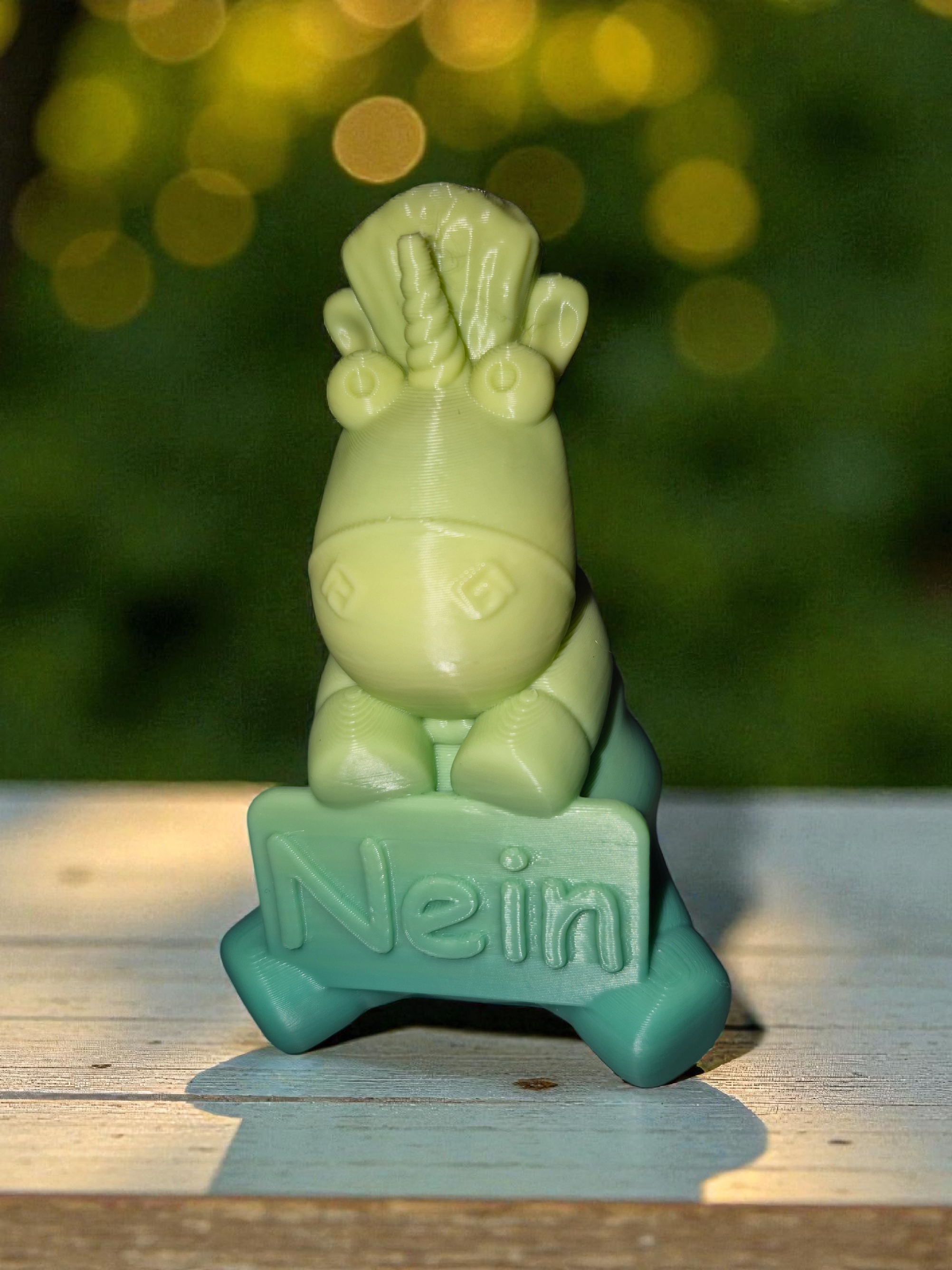 Ein grün gefärbtes Cannabis-ähnliches Tiermodell aus Kunststoff auf einem Holzuntergrund mit einem braunen Signal