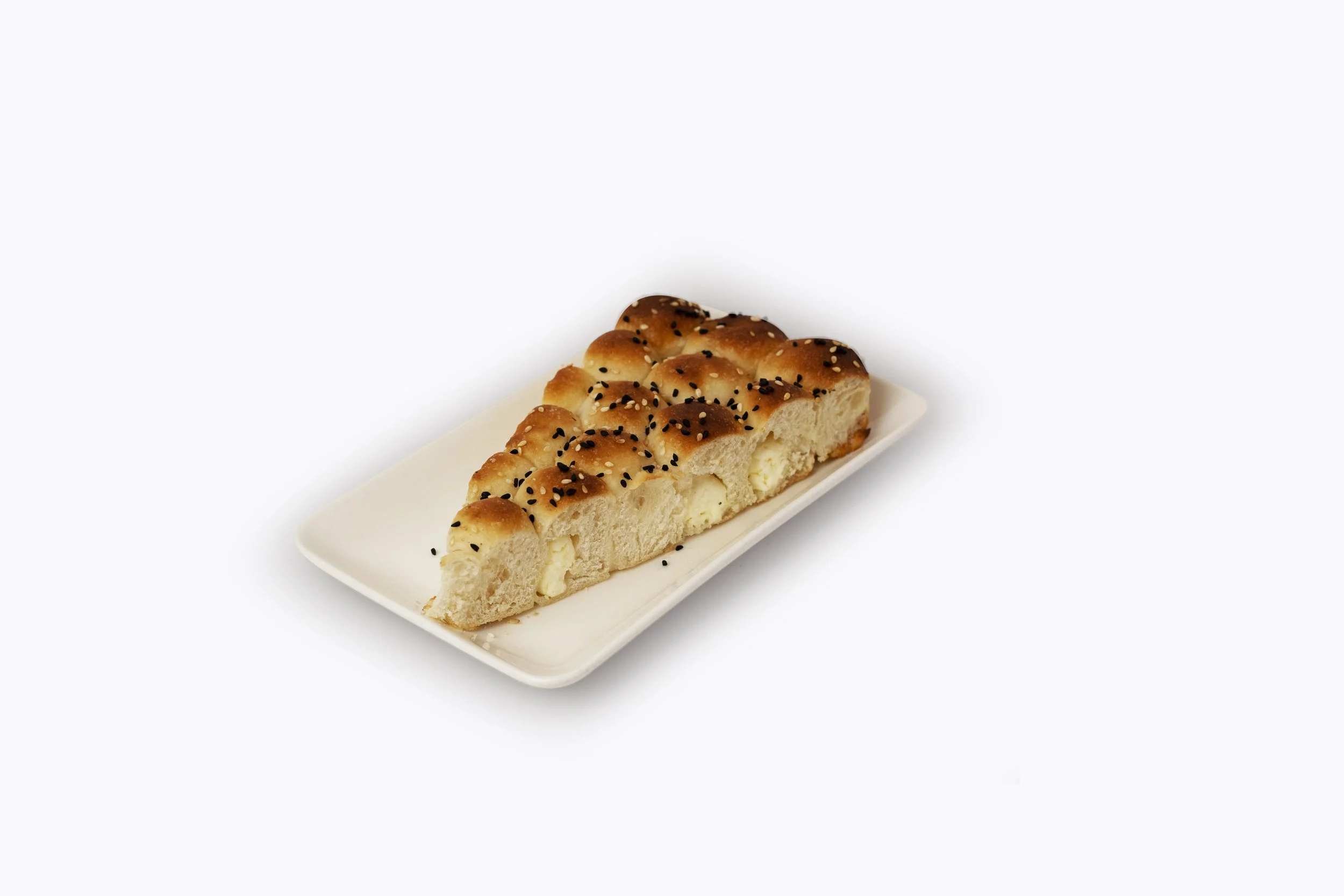 Slice of bread topped with black sesame seeds on a white rectangular plate
