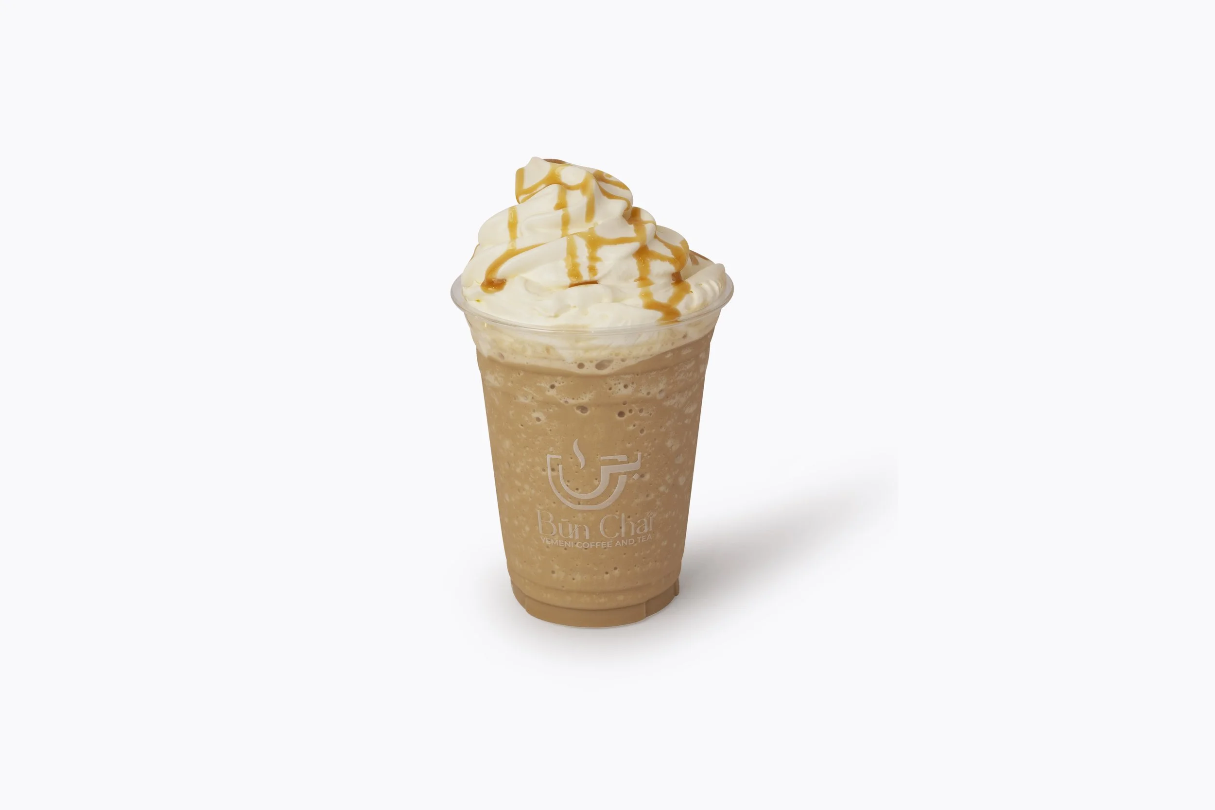 Iced coffee topped with whipped cream and caramel drizzle served in a clear plastic cup.
