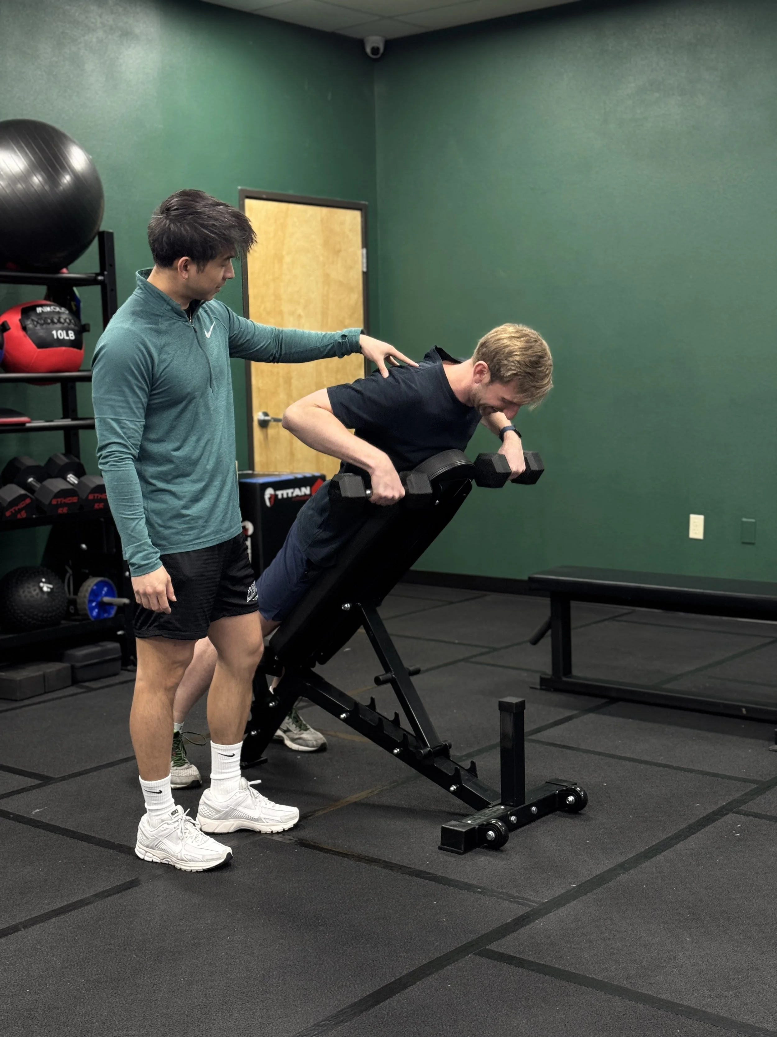 Personal trainer Joe improving a clients dumbbell row form for safety