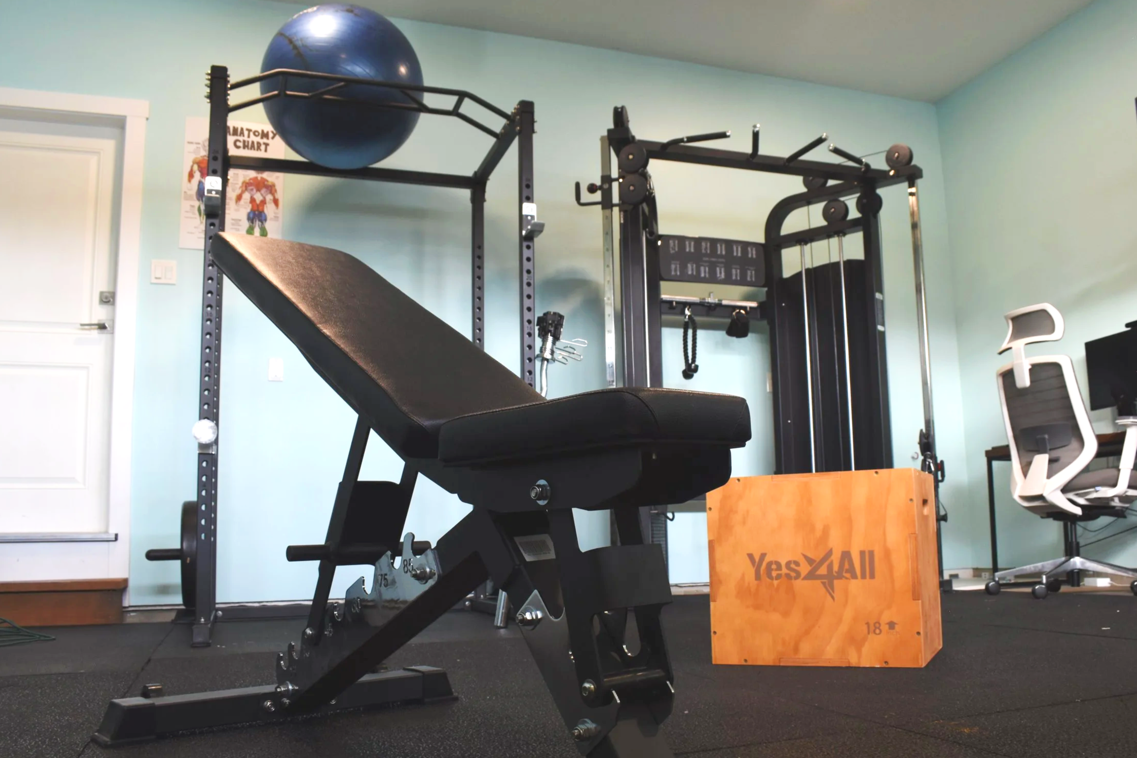 Private personal training gym with squat rack, adjustable bench, cable machine, and strength equipment in a clean garage training space.