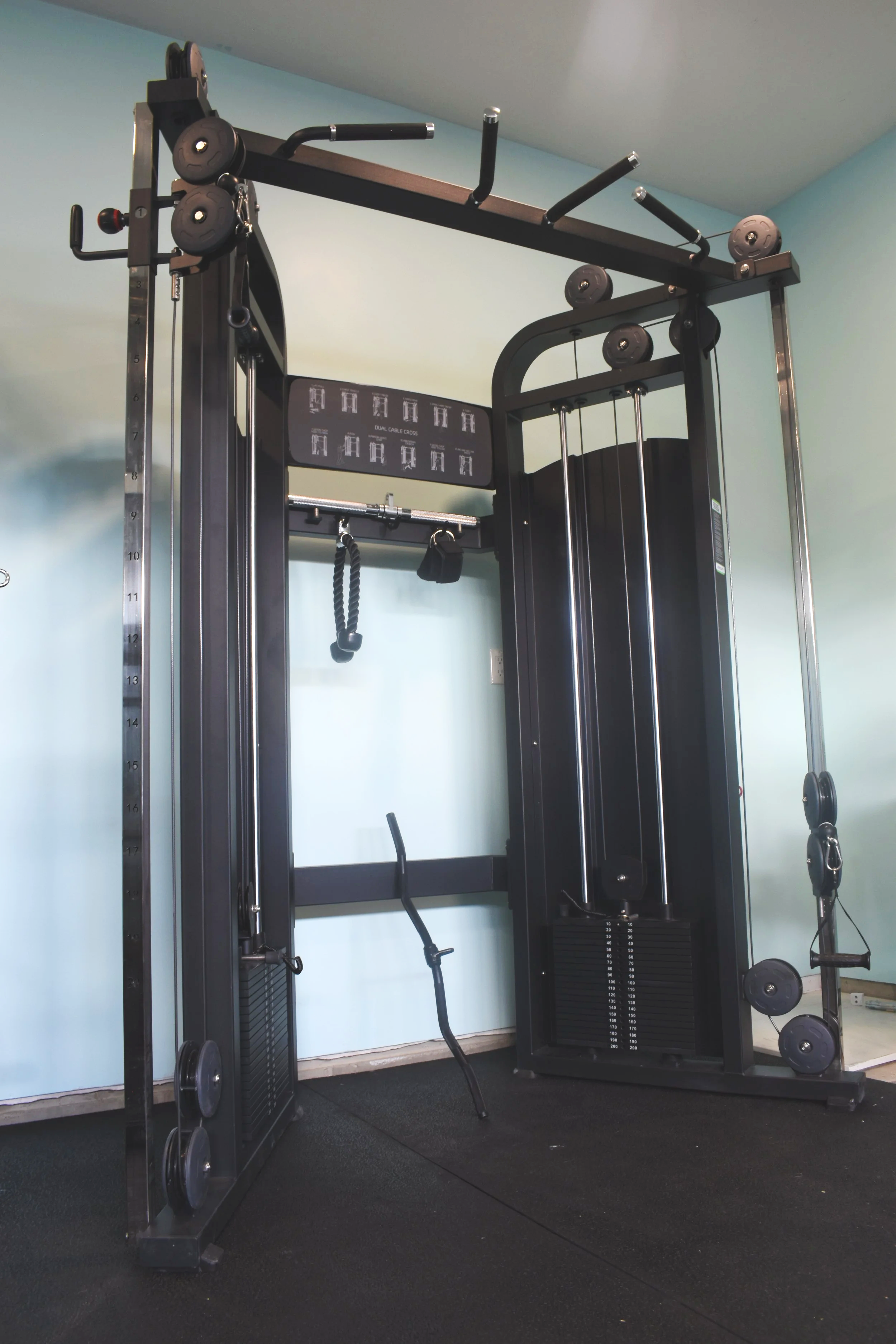 Dual adjustable cable machine with attachments for strength training exercises.