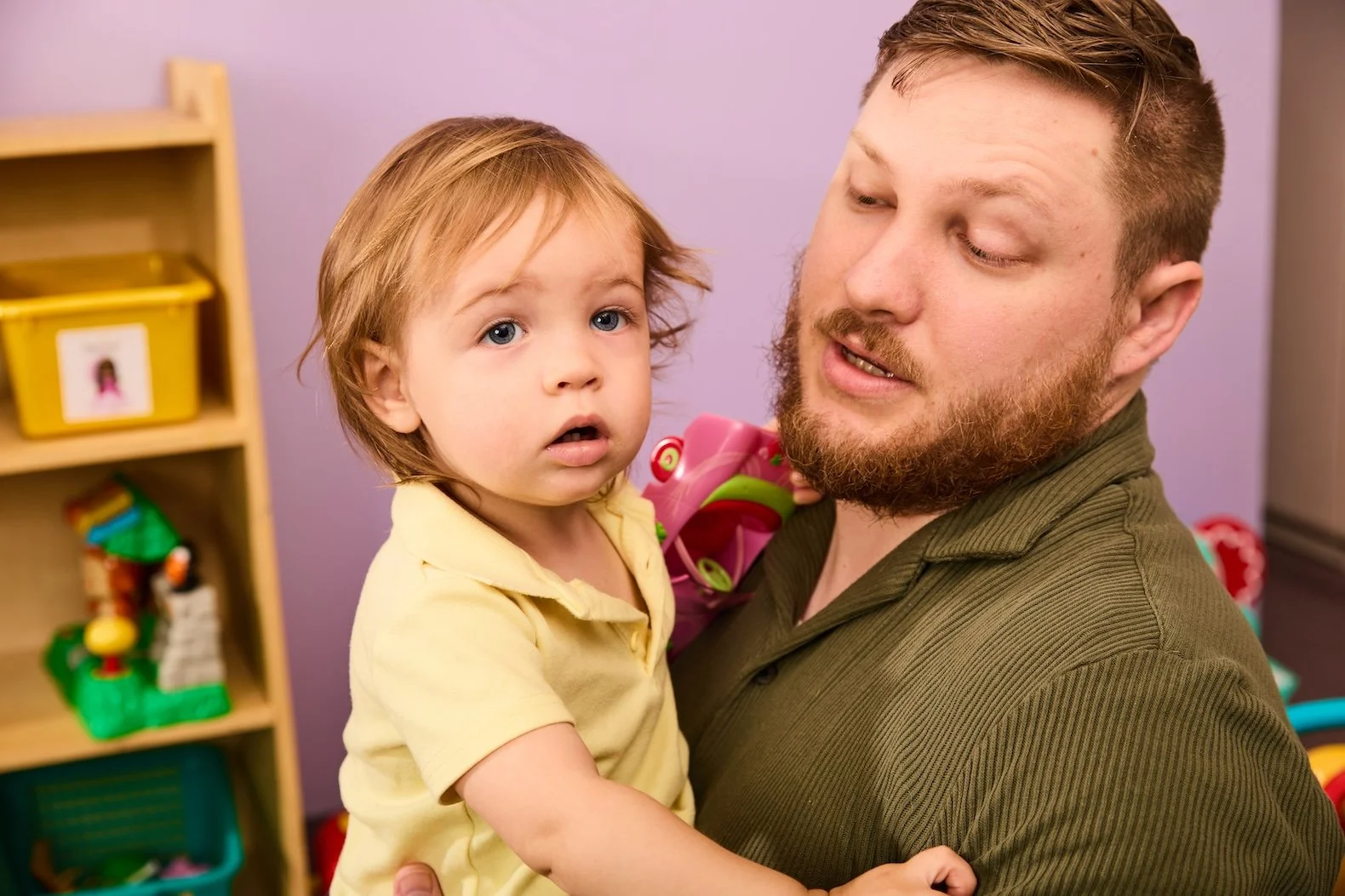 Young Dad plays with toddlers in a room with toys
