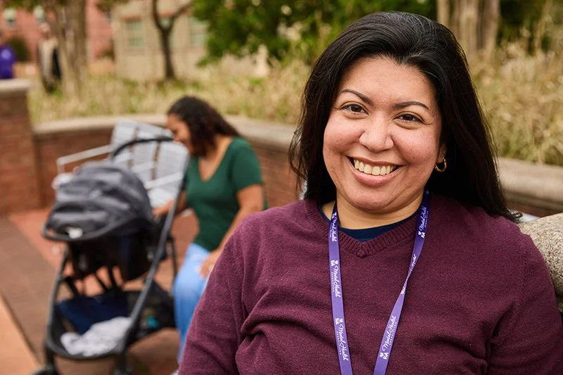 Smiling woman with dark hair wearing a maroon sweater and a purple lanyard from the Frederick County MHA