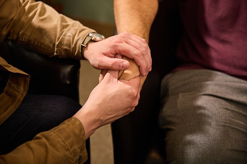 A person has their hand held and comforted by another person, suggesting a supportive or comforting gesture.
