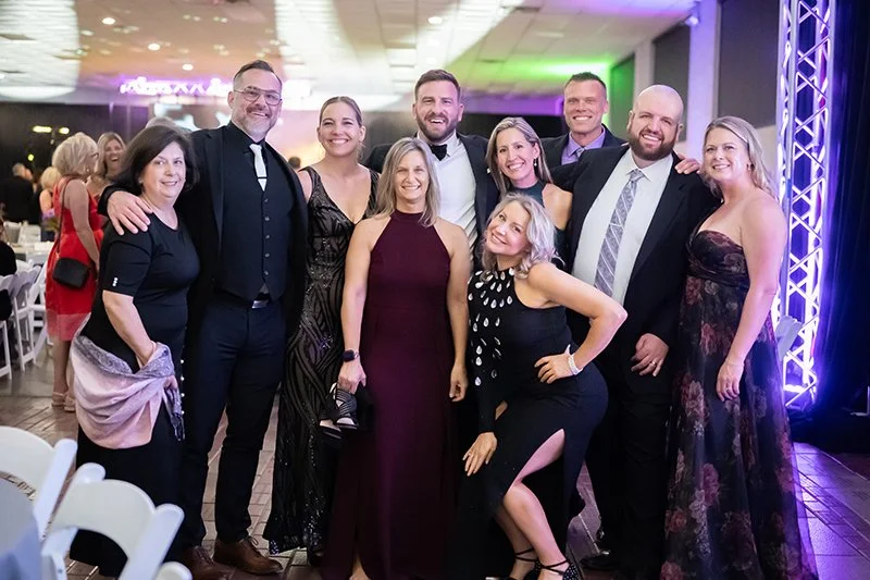 Group of ten people at the Catoctin Affair, smiling, with a colorful lighting backdrop.