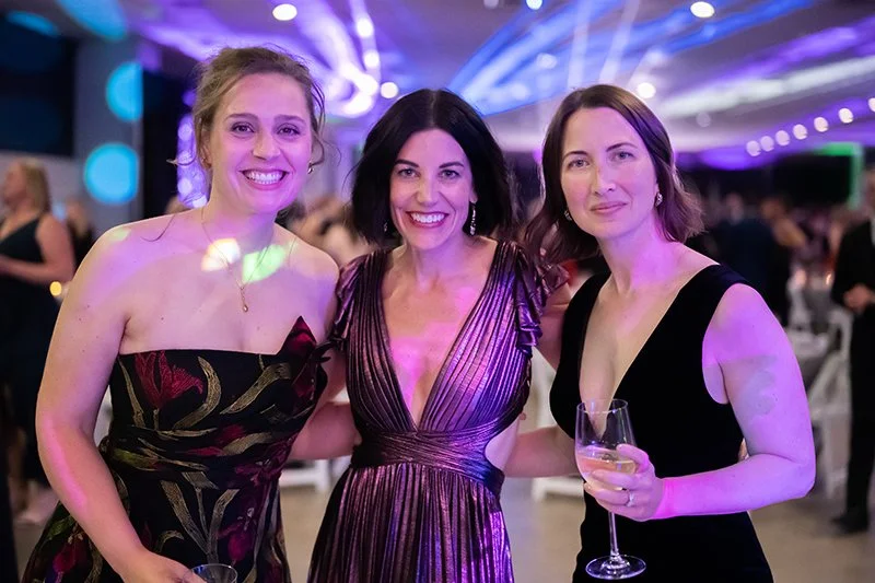 Three women in evening dresses smiling and holding wine glasses at  the Catoctin Affair 