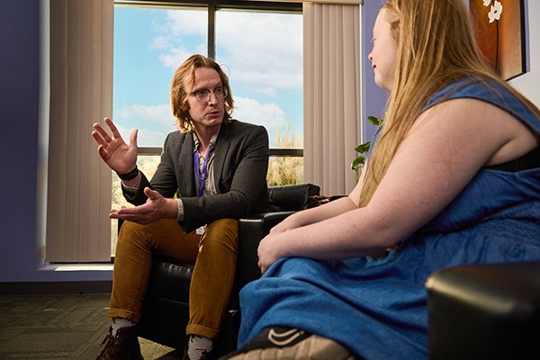 man in blazer kindly speaking with a woman in a well lit office