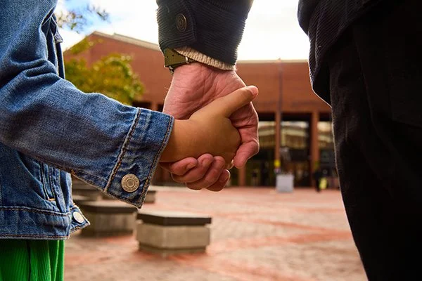 child with demin shirt holds hands with adult in front of Frederick County courthouse