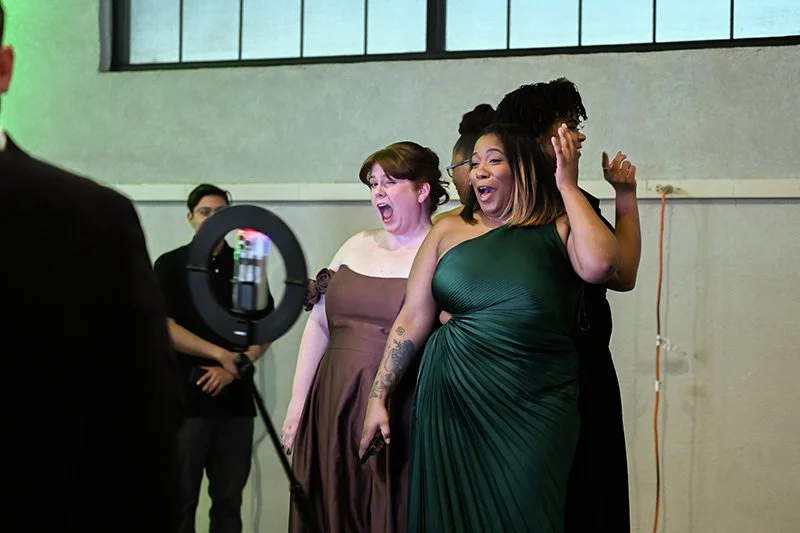 A group of diverse women in elegant dresses happily reacting to someone at the Catoctin Affair