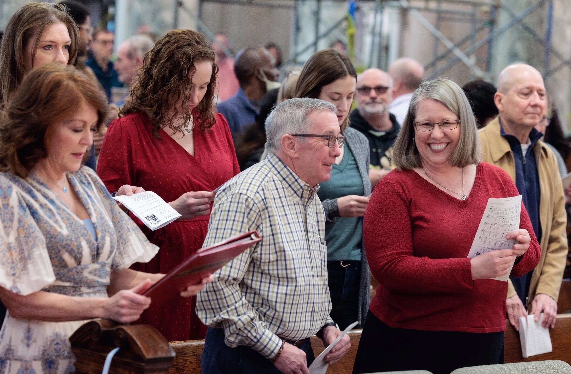 People standing in church pews, singing or reading hymn sheets during a service.