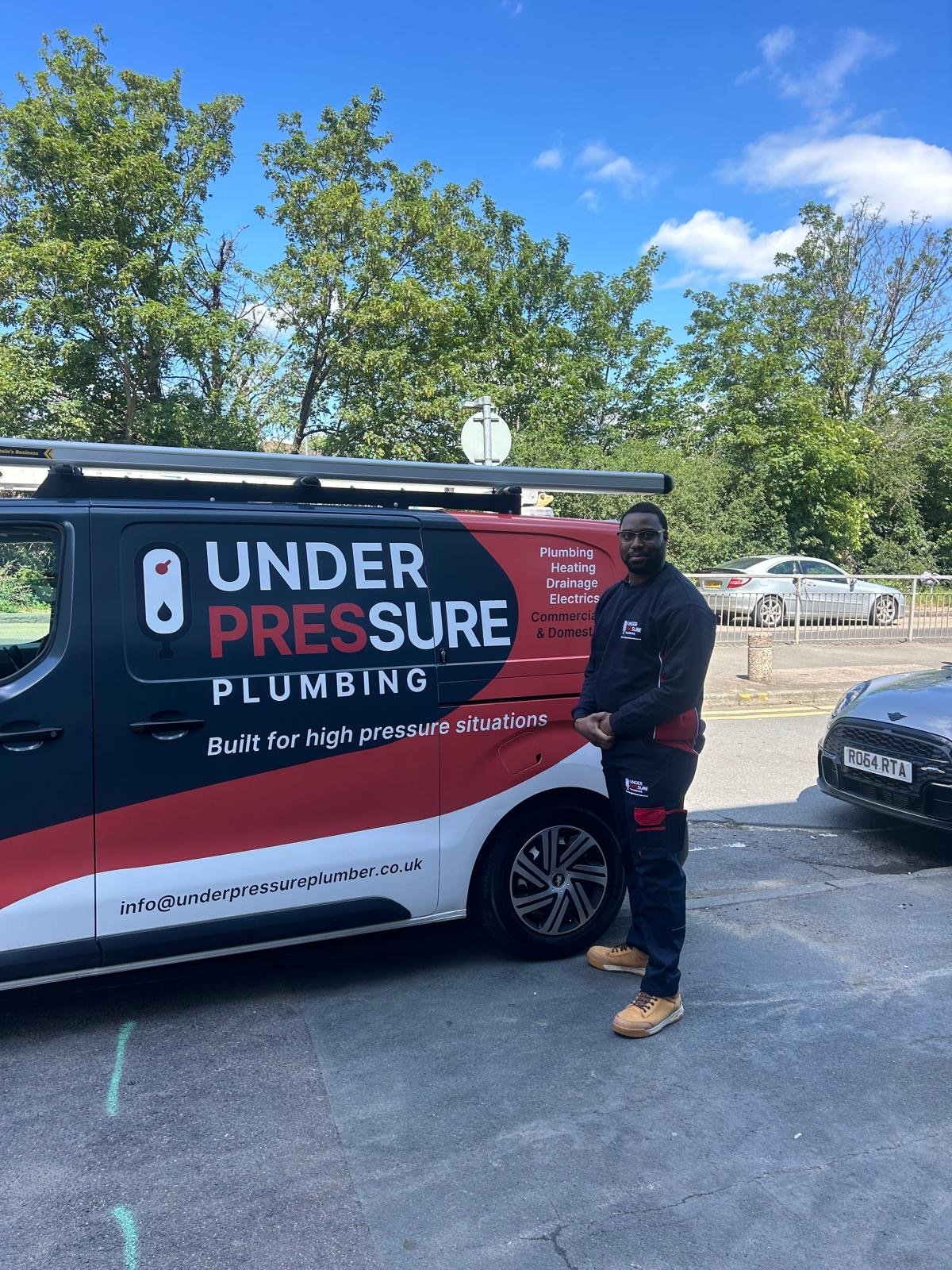 Drainage engineer from Under Pressure Plumbing standing beside a company van in London.