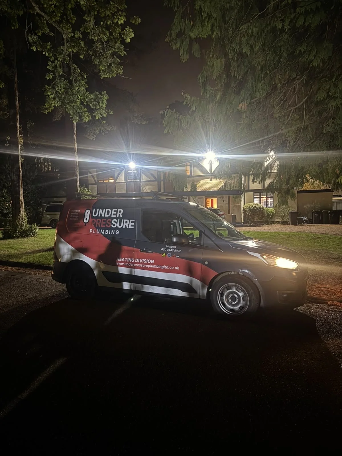 Under Pressure Plumbing branded service van parked outside a residential property at night.