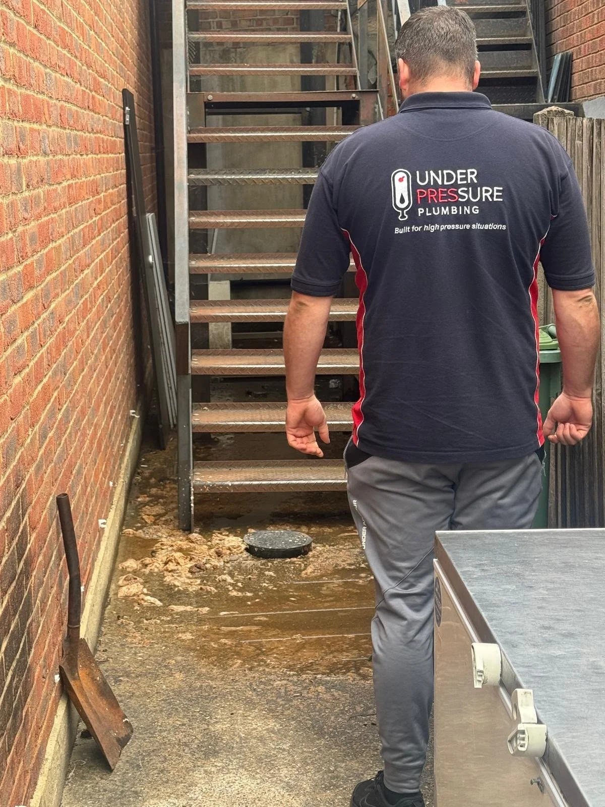 Under Pressure Plumbing engineer wearing company uniform on-site at a residential property.