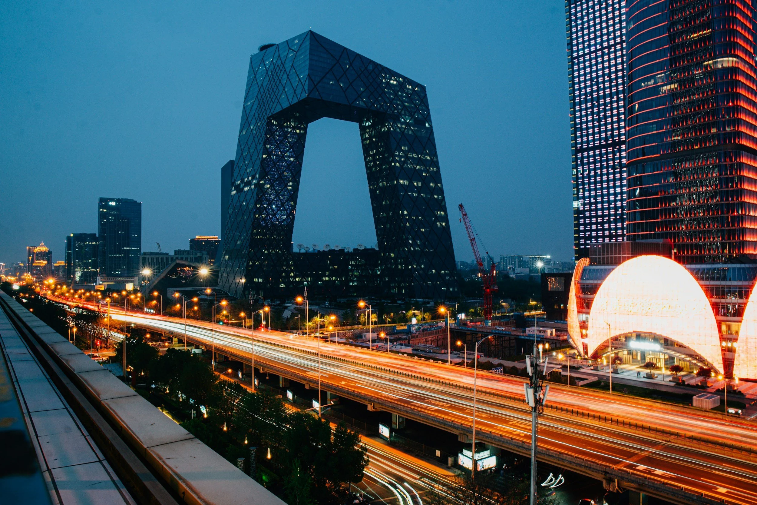 Night view of Beijing Olympic Tower with illuminated skyscrapers and traffic streaks on the highway, representing board advisory that helps high‑growth fintech and B2B platform companies navigate complex strategic decisions.