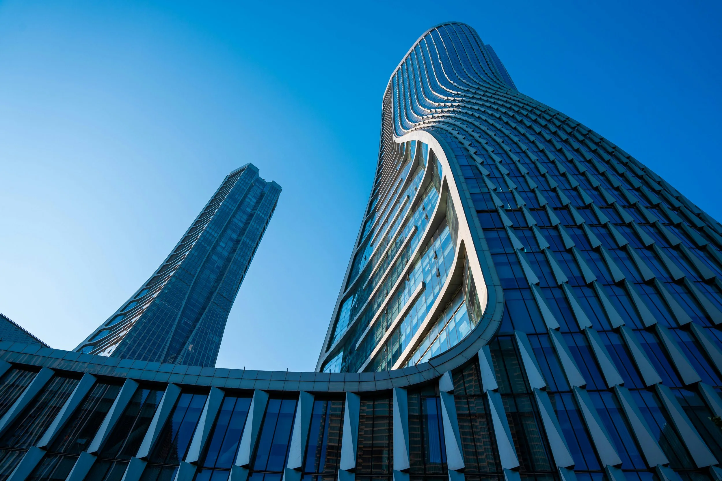 Low-angle view of modern glass skyscrapers against a clear blue sky, representing high‑growth fintech and B2B platform companies we work with.