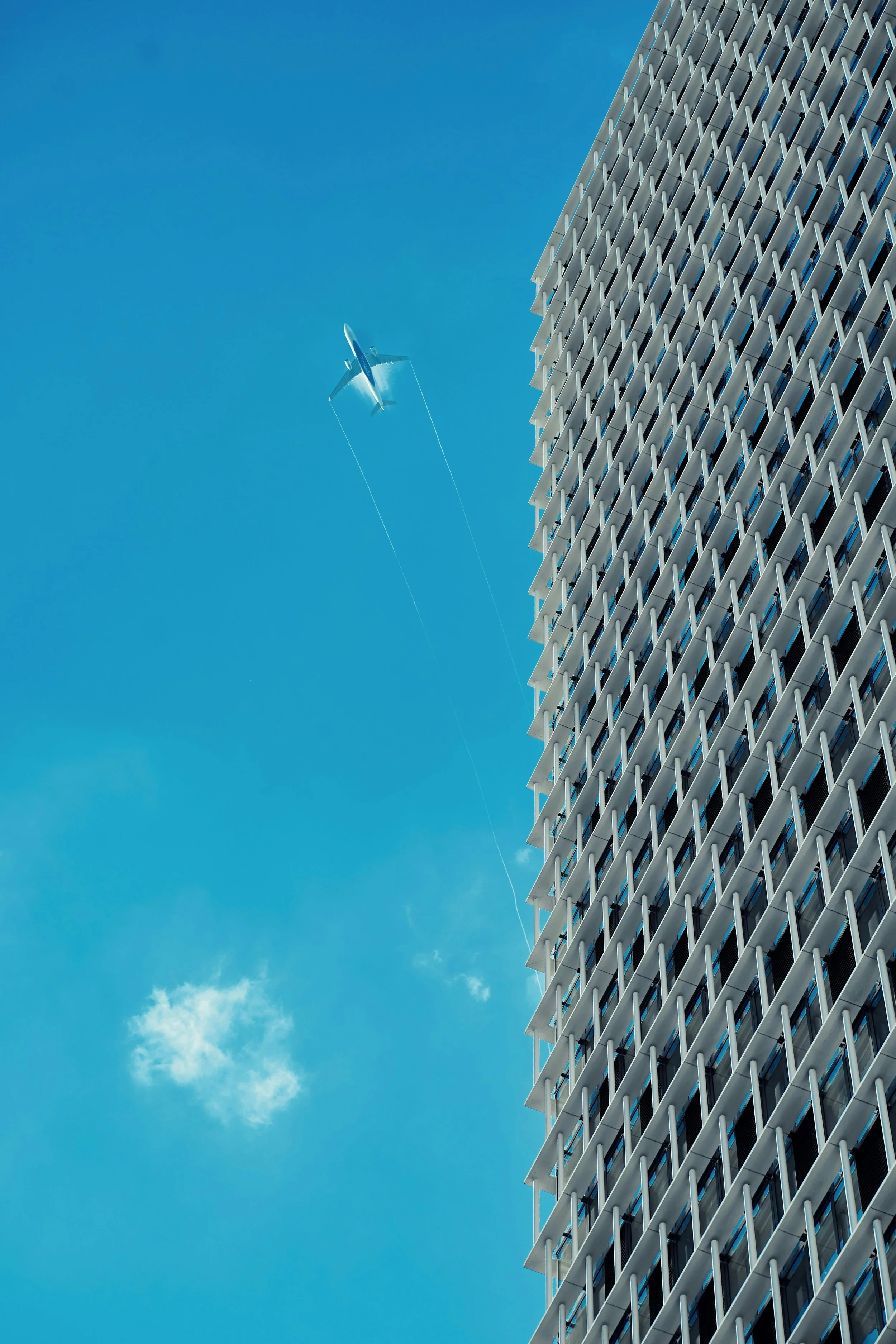 A plane flying high in the sky beside a tall modern building, symbolising our international M&A and fundraising advisory experience for fintech and B2B platform companies.