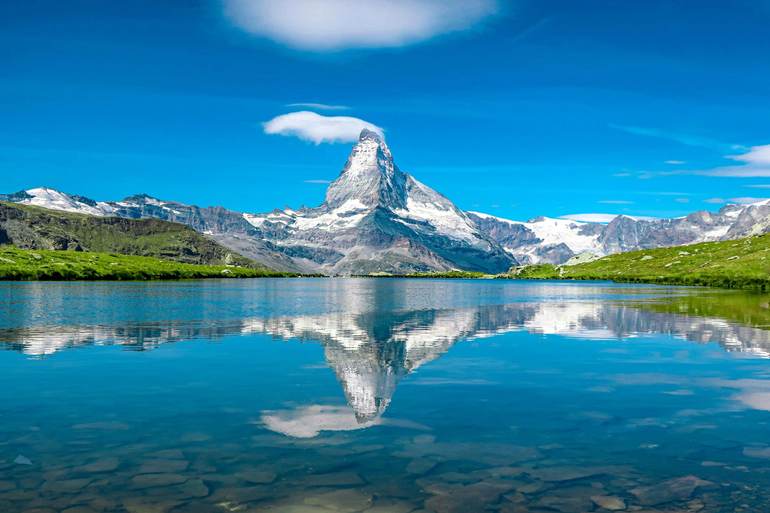 Snow‑capped mountain peak reflected in a calm lake under a blue sky, illustrating our structured, step‑by‑step M&A and fundraising advisory process to help fintech and B2B platforms scale.