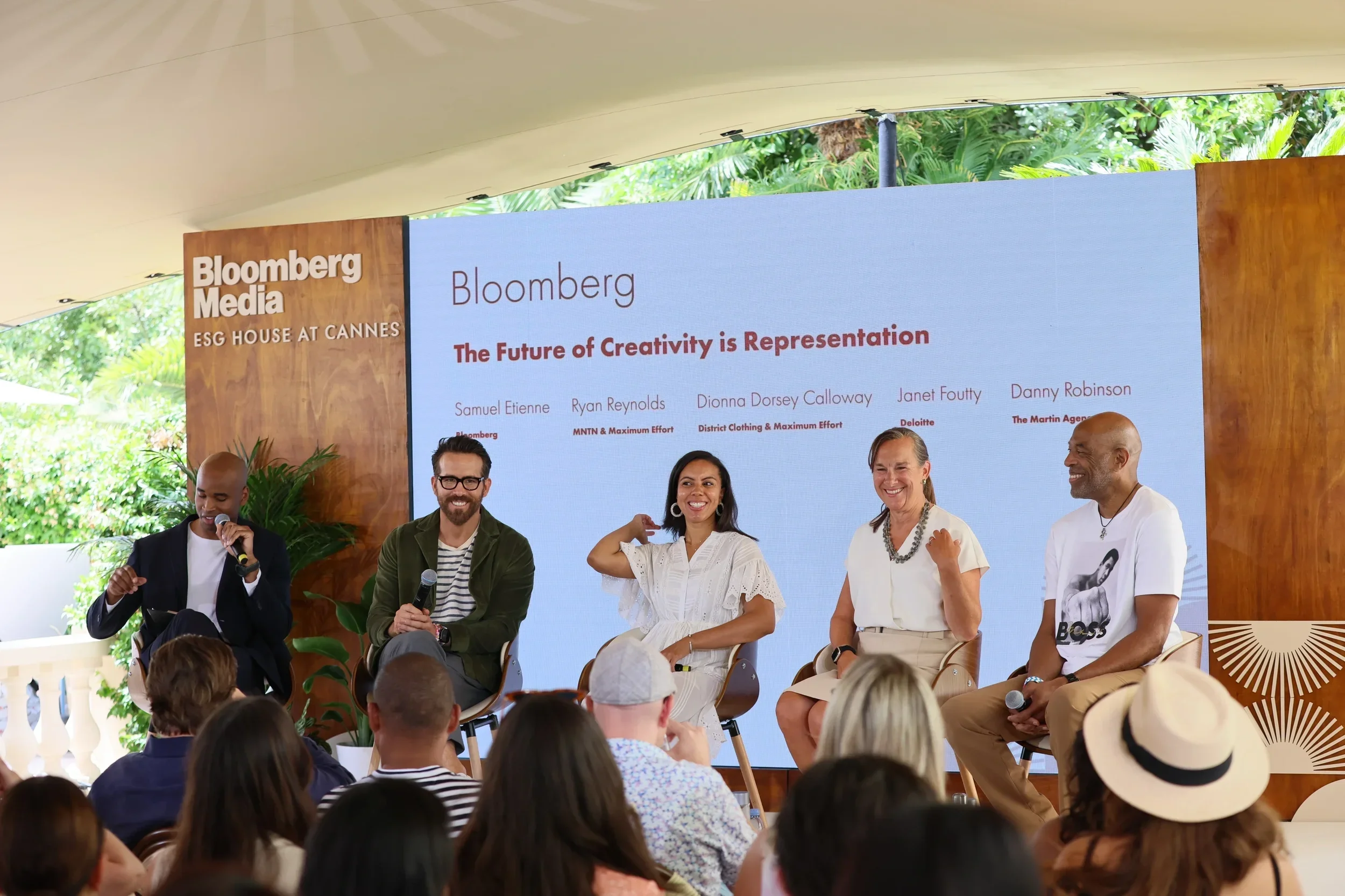 A panel discussion at a Bloomberg Media event titled "ESG House at Cannes" with five speakers seated on stage and an audience in front, outdoors with greenery in the background.