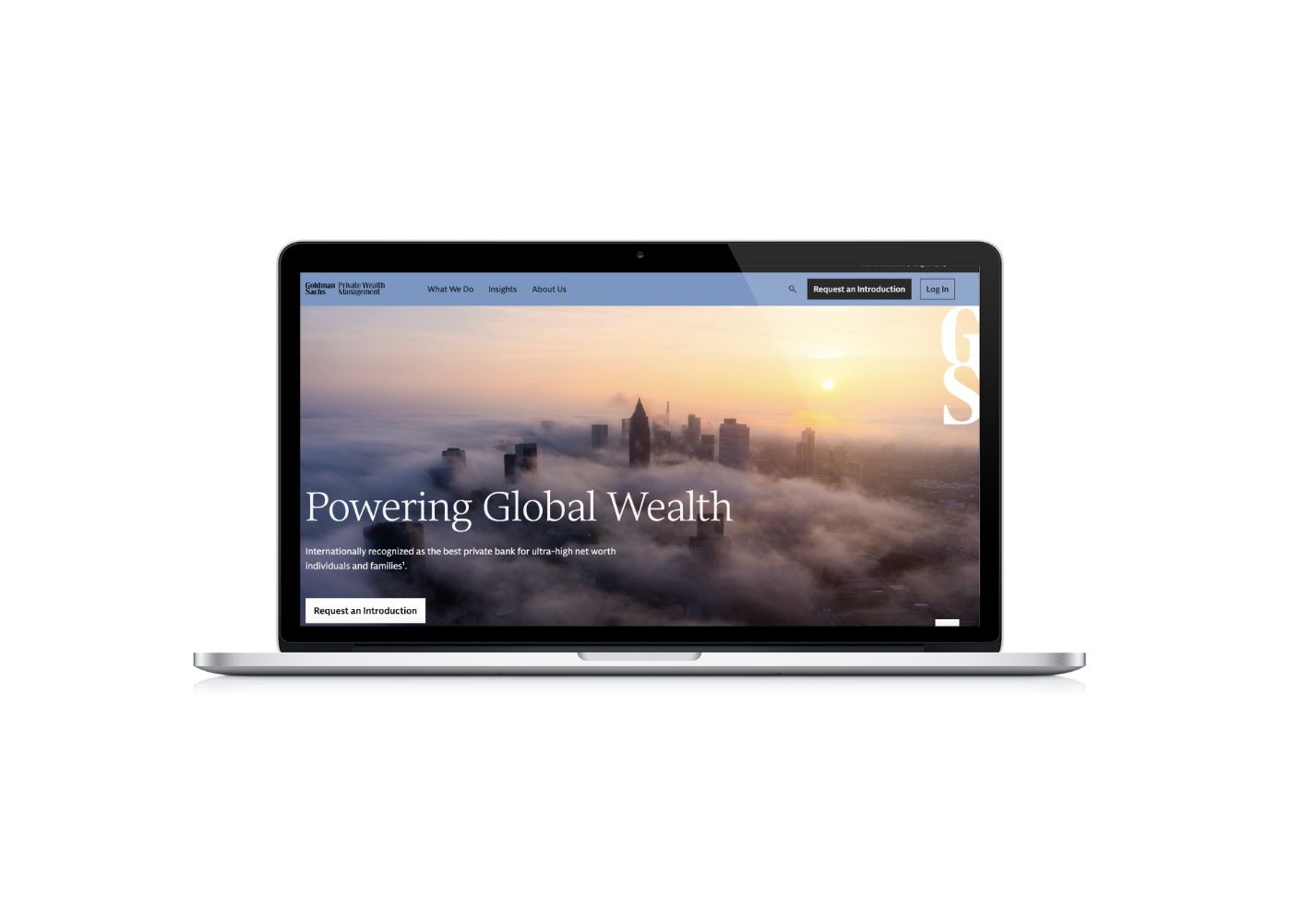 Laptop displaying Goldman Sachs Private Wealth Management website with a city skyline at sunset and fog, featuring the text 'Powering Global Wealth'.