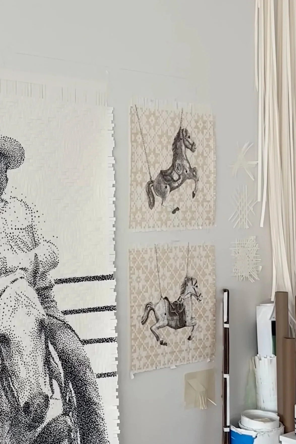 Wall with two framed prints of vintage style carousel horses, surrounded by various decorative wall art and objects.