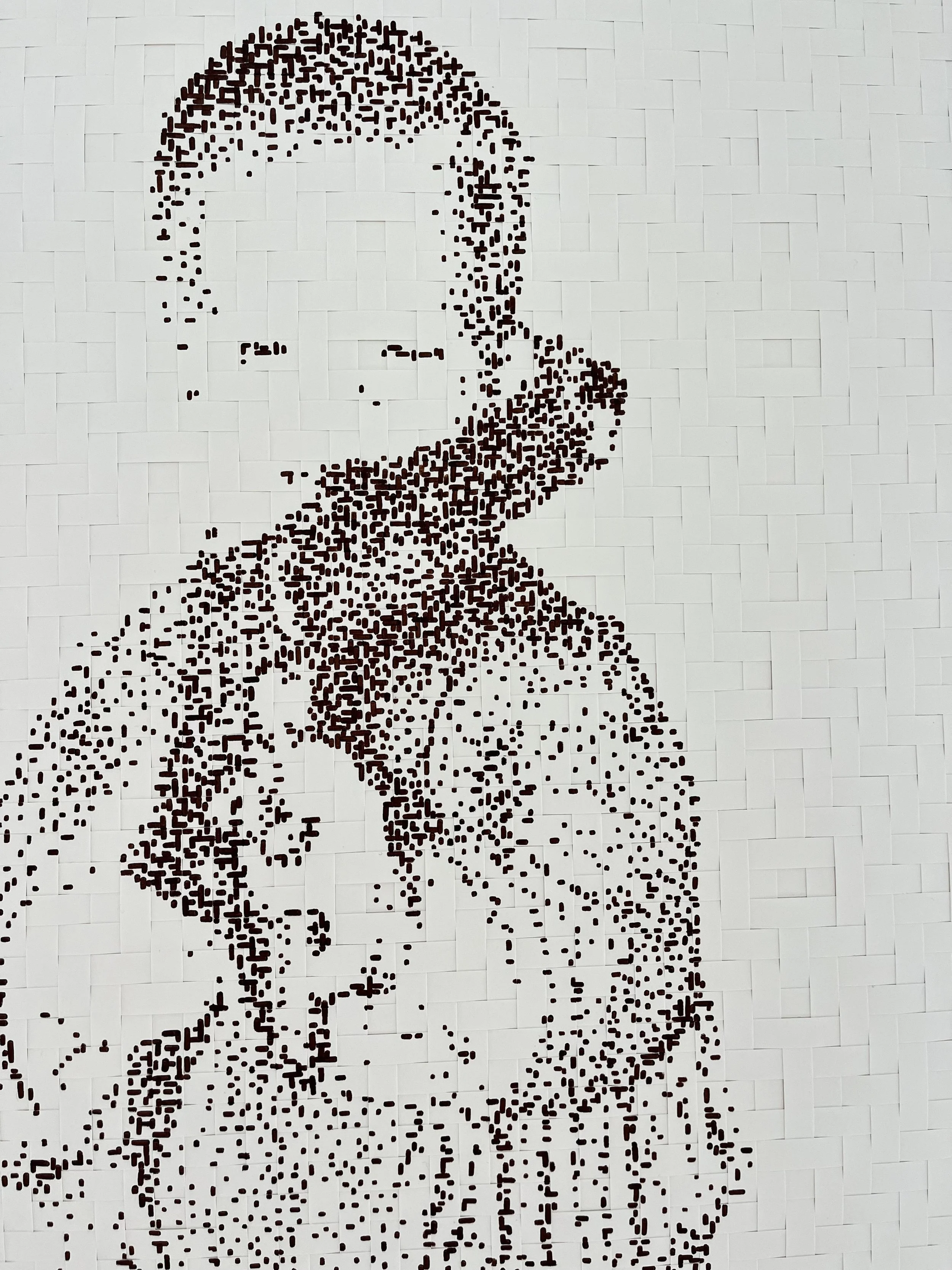 Dot mosaic mural of a boy holding a basketball, on a white tiled wall.