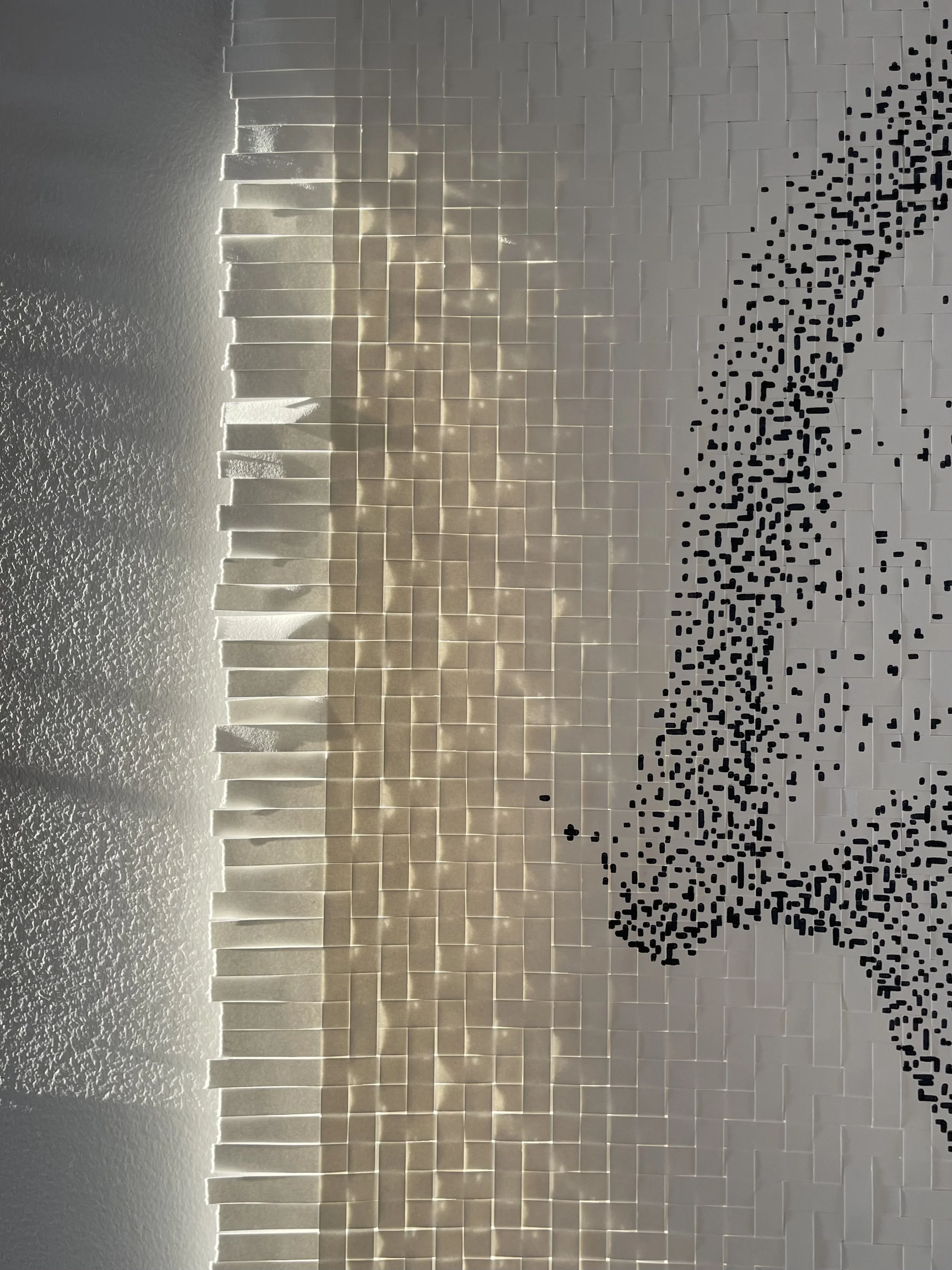 A wall with a 3D art installation featuring rectangular tiles creating a wave pattern, with a section of black pixels forming a curved shape.