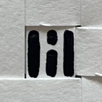 A wall with a cutout revealing a cartoonish face painted on a piece of paper or material behind it