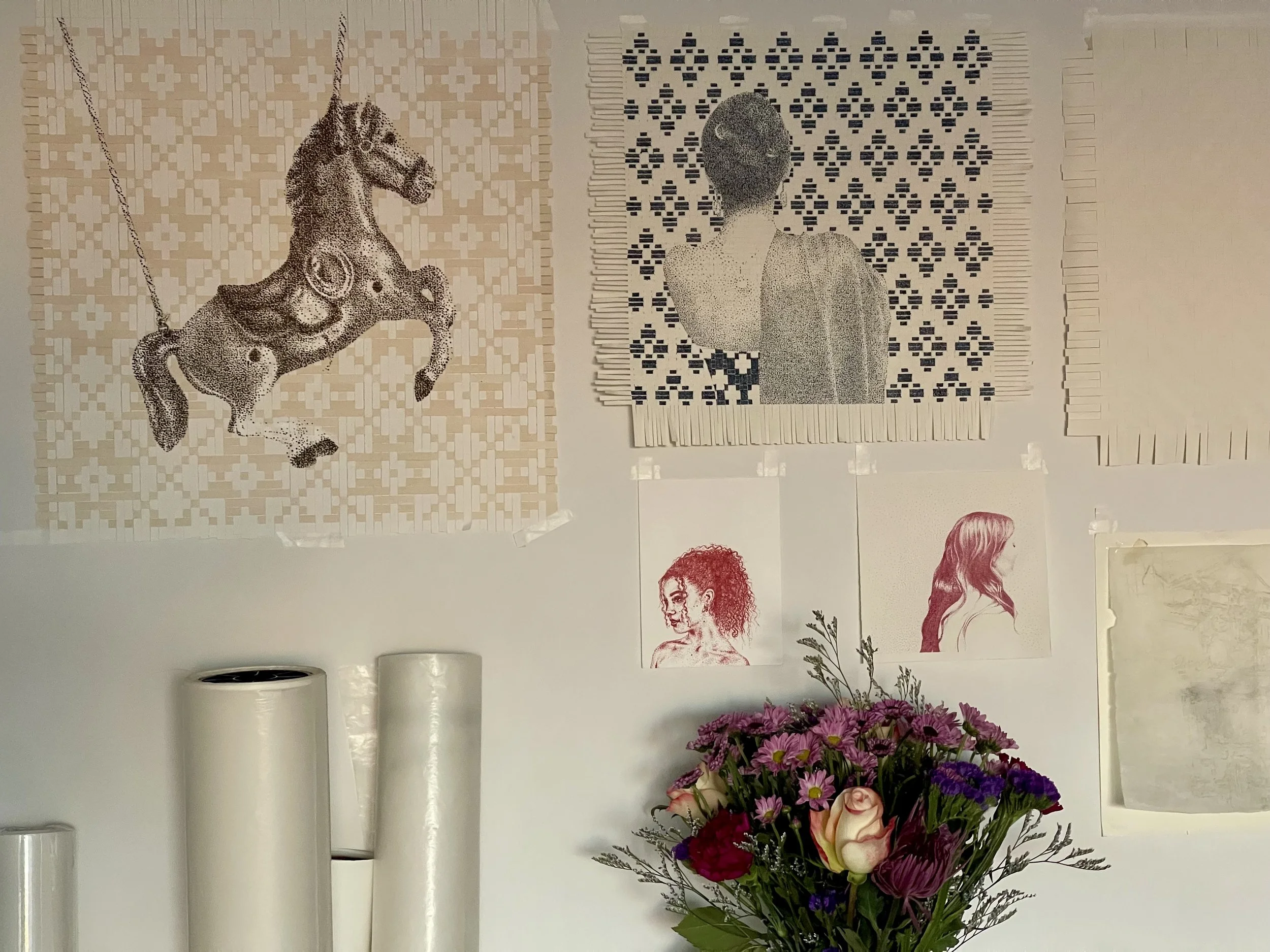 Wall decorated with various art prints and a bouquet of colorful flowers in the foreground.
