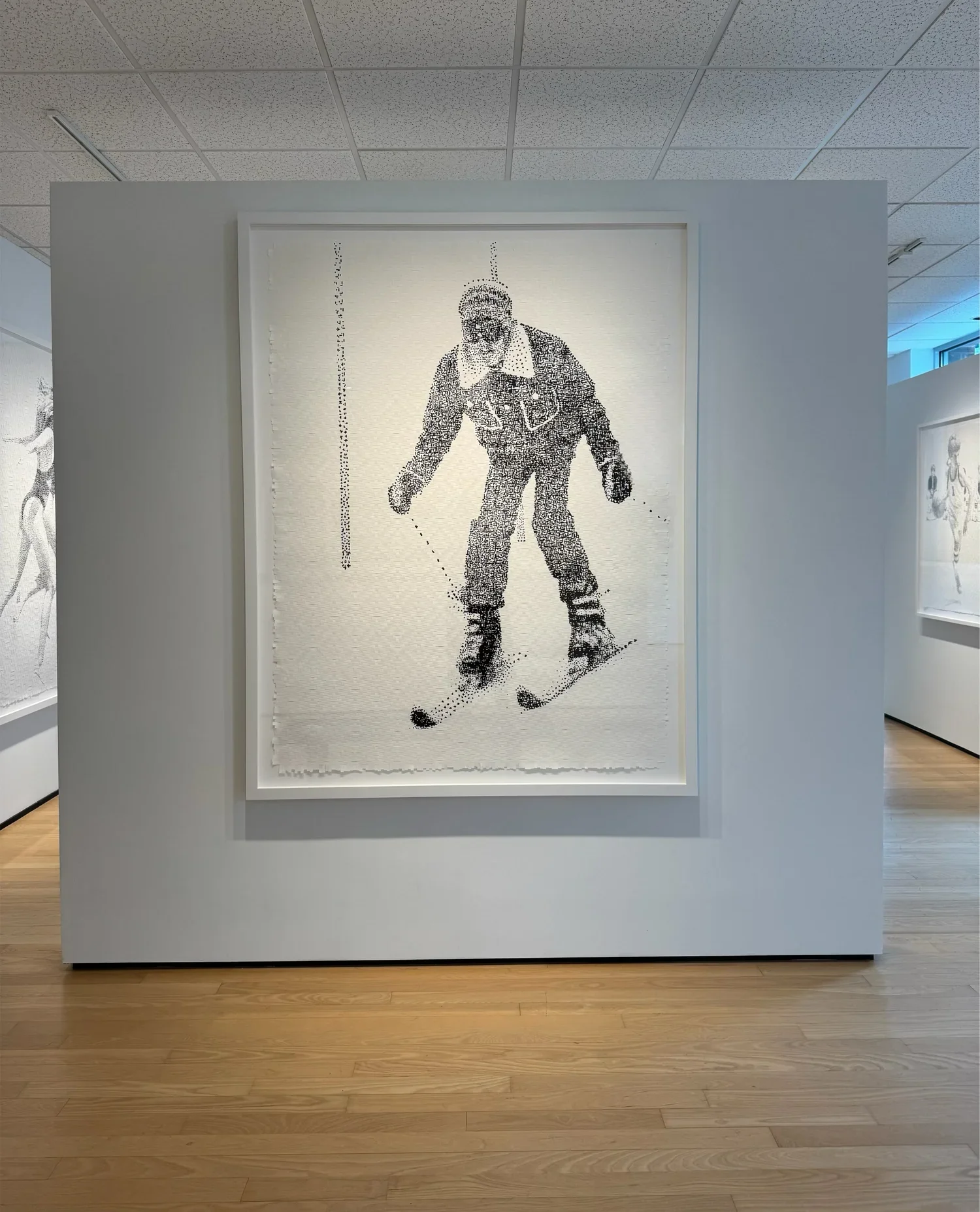 Pixelated artwork of a person ice skating, displayed on a white gallery wall.